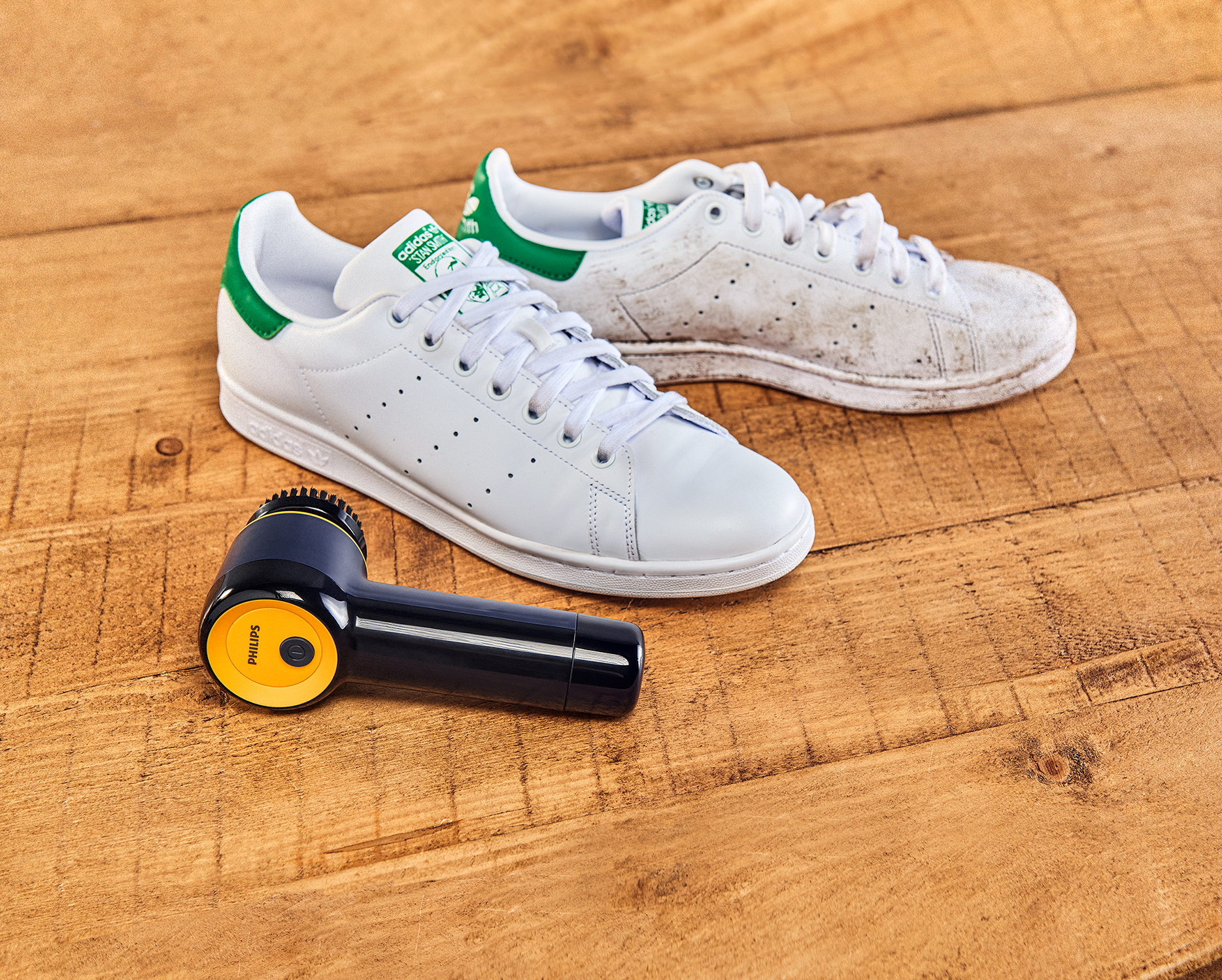Schoon en vuil witte sneakers met een schoonmaakborstel en houten achtergrond.