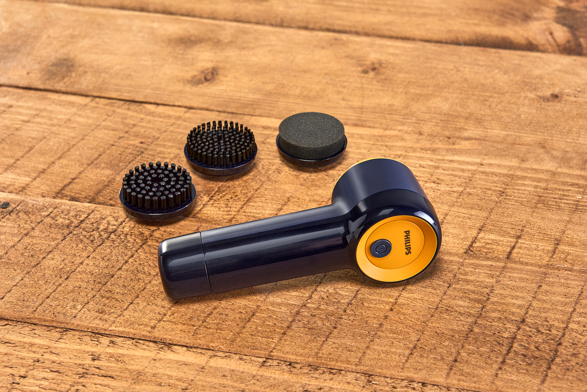 Schoenpoetsmachine met drie borstelkoppen en een oranje aan/uit-knop.