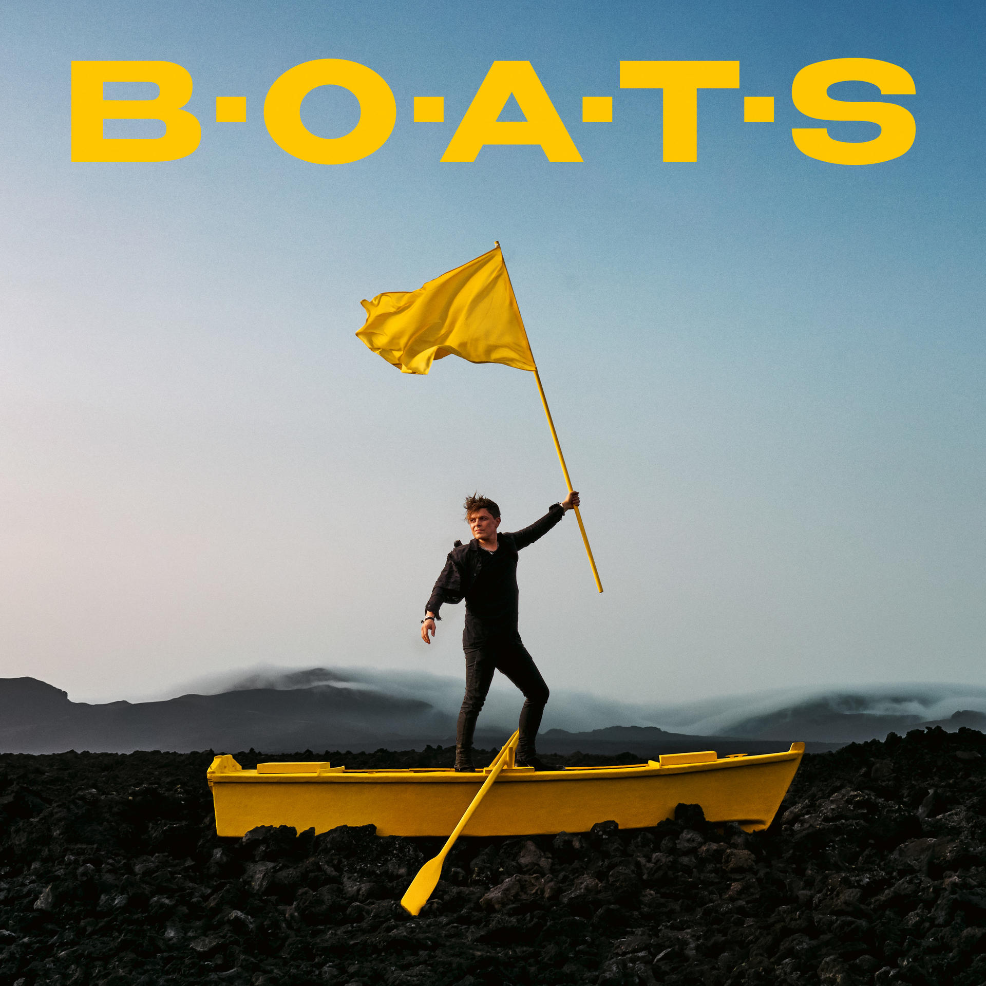 Ein Mann steht in einem gelben Boot und hält eine gelbe Flagge. Über ihm steht das Wort „B.O.A.T.S“.