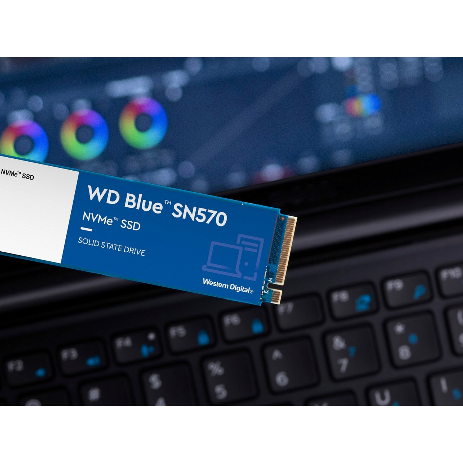 SSD NVMe WD Blue SN570 azul en un teclado de portátil, mostrando la etiqueta de la unidad.