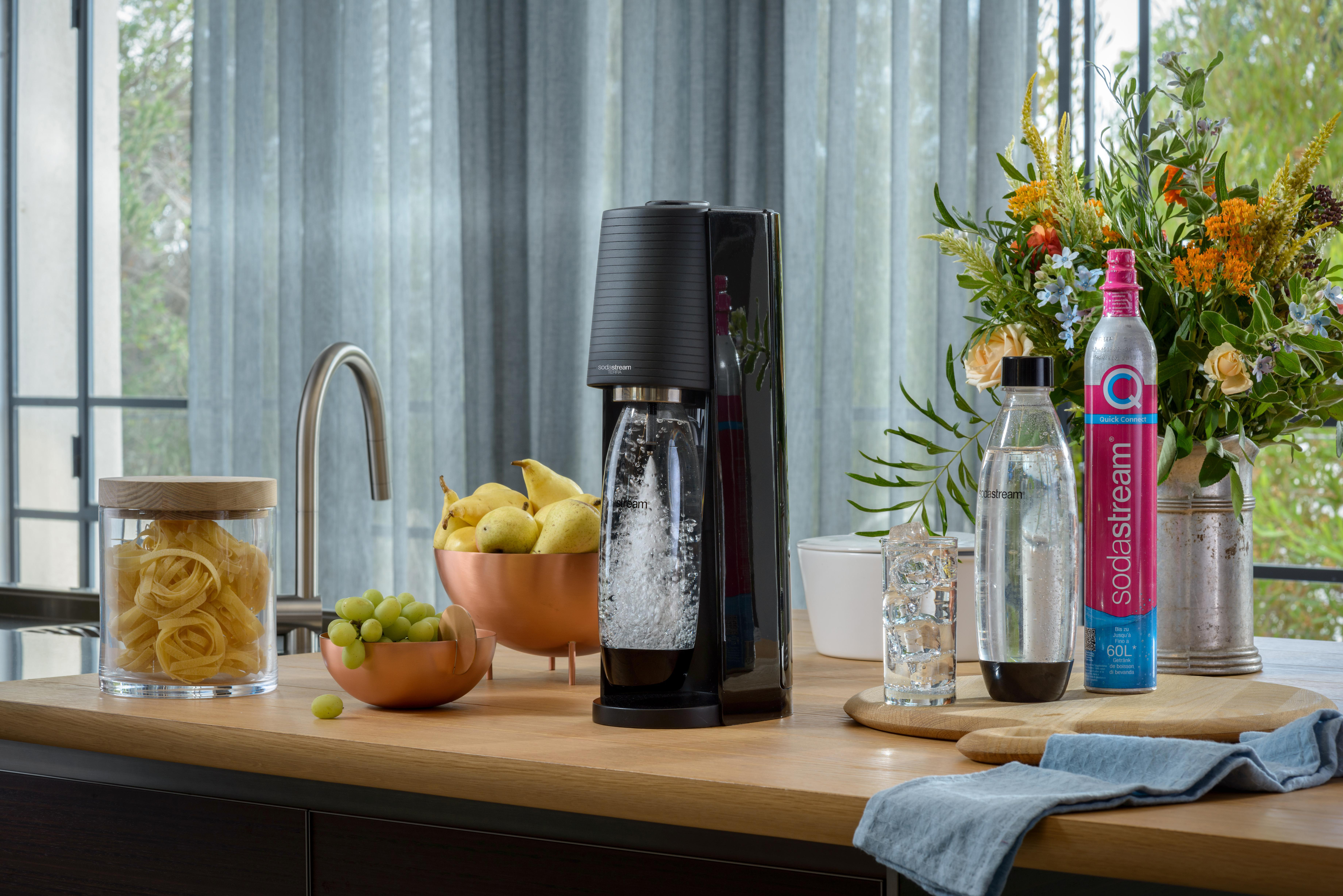 SodaStream-Maschine mit Sprudelwasser und Zutaten auf einer Arbeitsplatte.