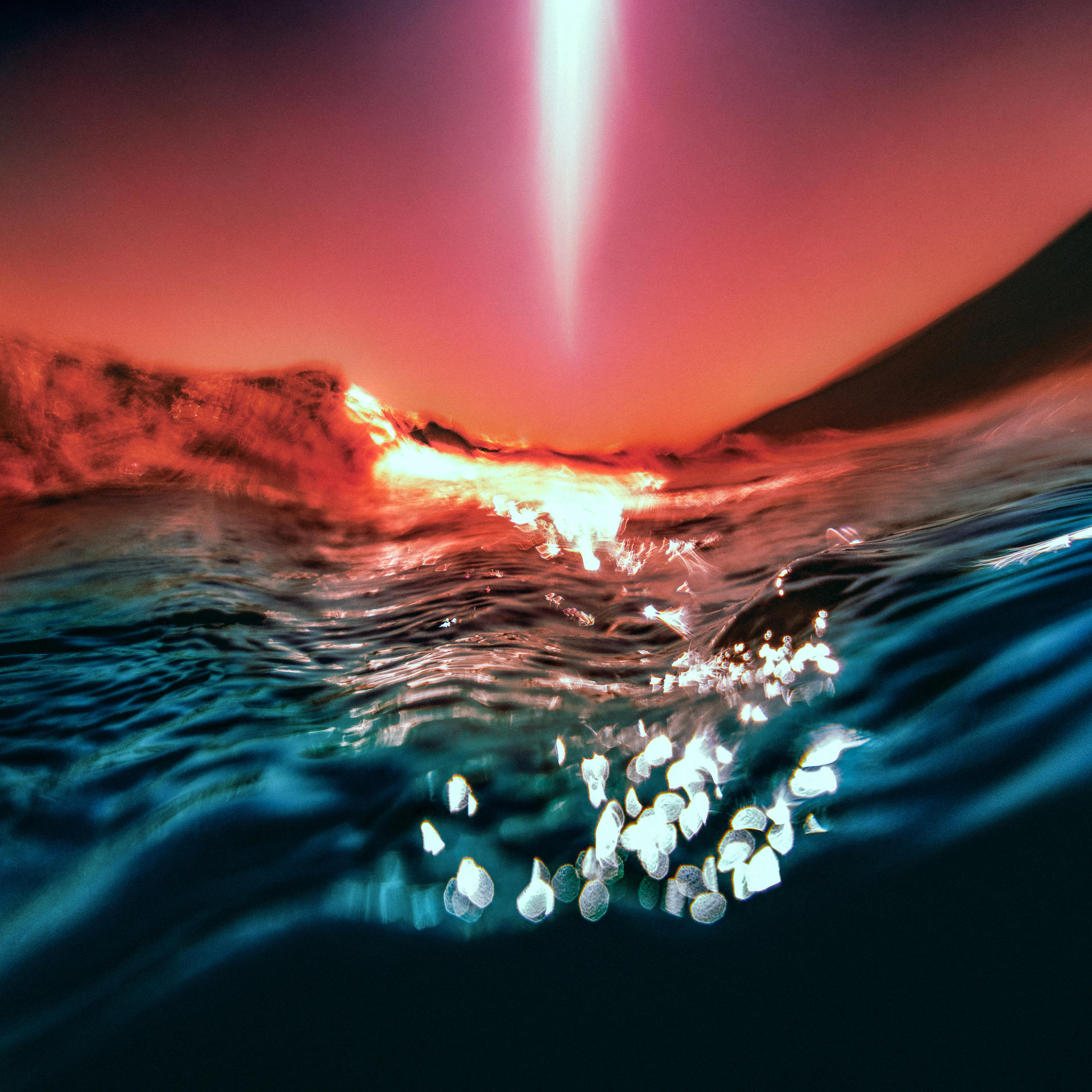 Surface de l'eau reflétant la lumière. Un rayon descend du ciel rouge.