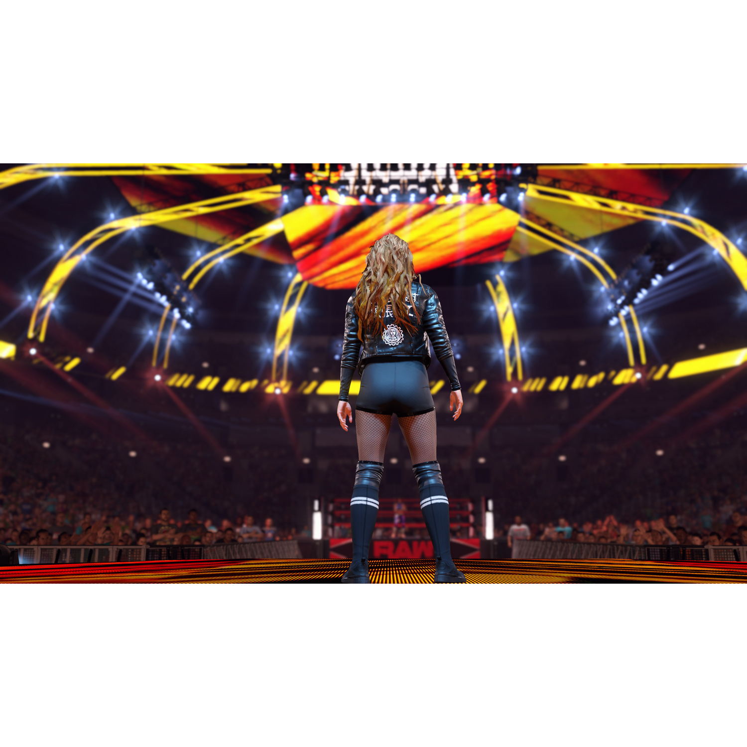Un luchador está en el ring, de espaldas a la cámara, bajo luces brillantes.