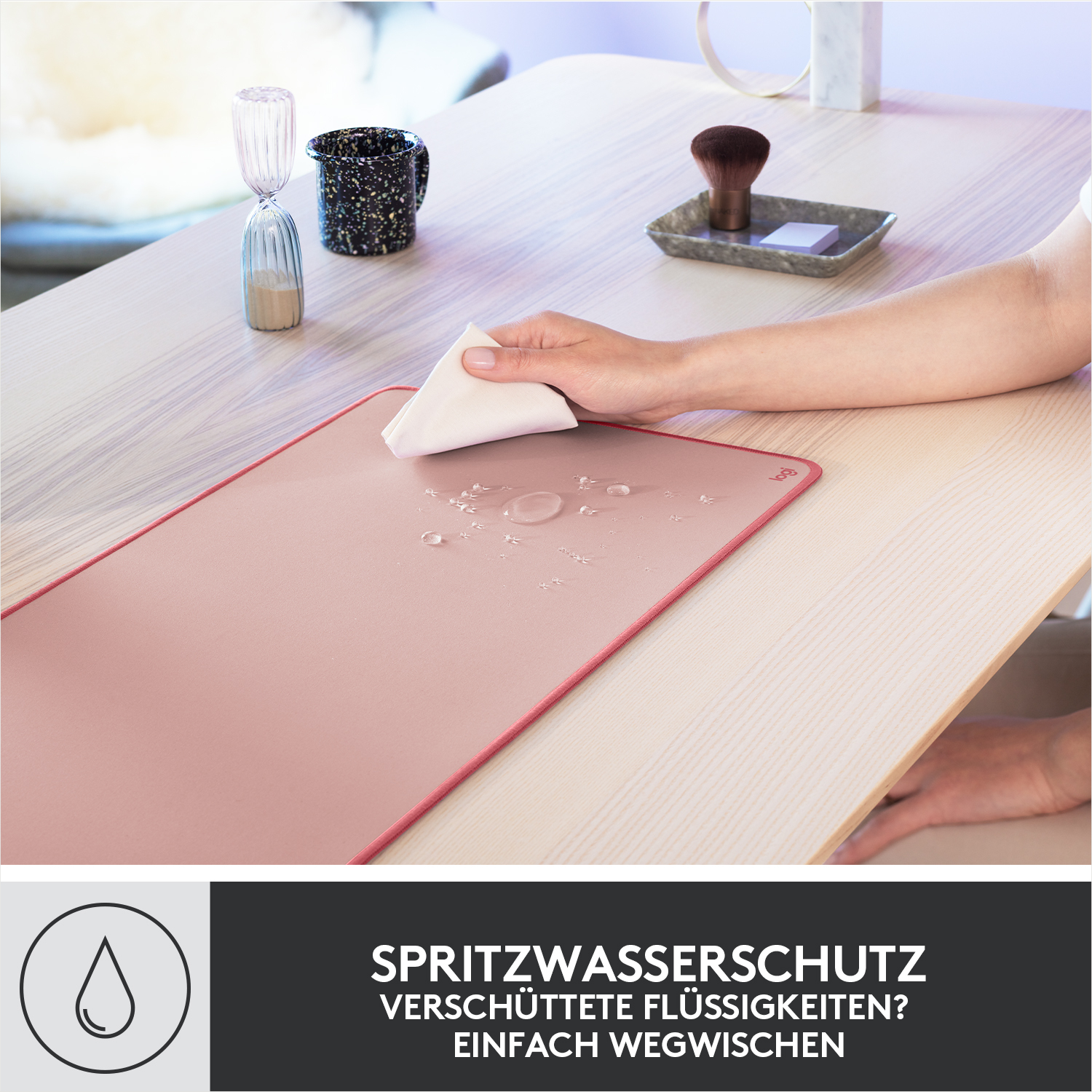 Eine Hand wischt mit einem Tuch Flüssigkeit von einer rosafarbenen Matte.
