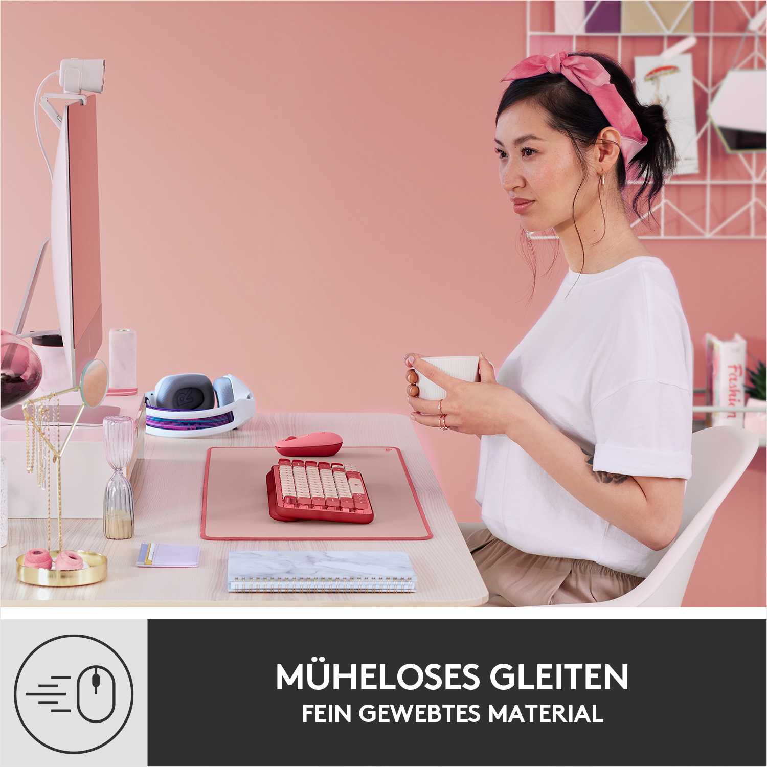 Frau mit rosa Kopftuch sitzt am Schreibtisch, hält Tasse. Pinke Tastatur.