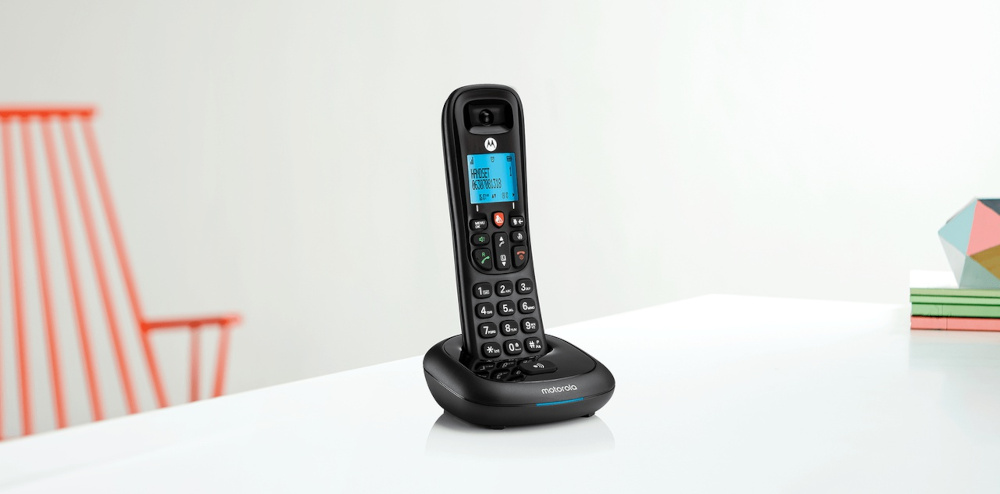 Zwarte draadloze telefoon op een oplaadbasis. De telefoon heeft een scherm en knoppen.