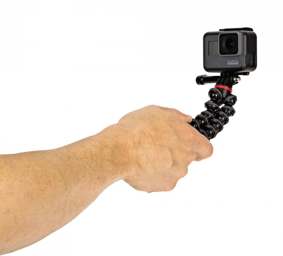 Egy kéz GoPro kamerát tart egy hajlékony állványon, fehér háttér előtt.