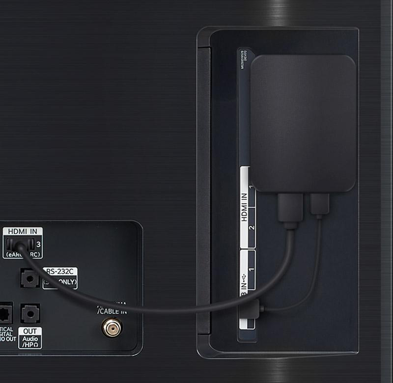 Rückseite des Fernsehers mit HDMI-Anschlüssen, einer schwarzen Box und Kabeln.