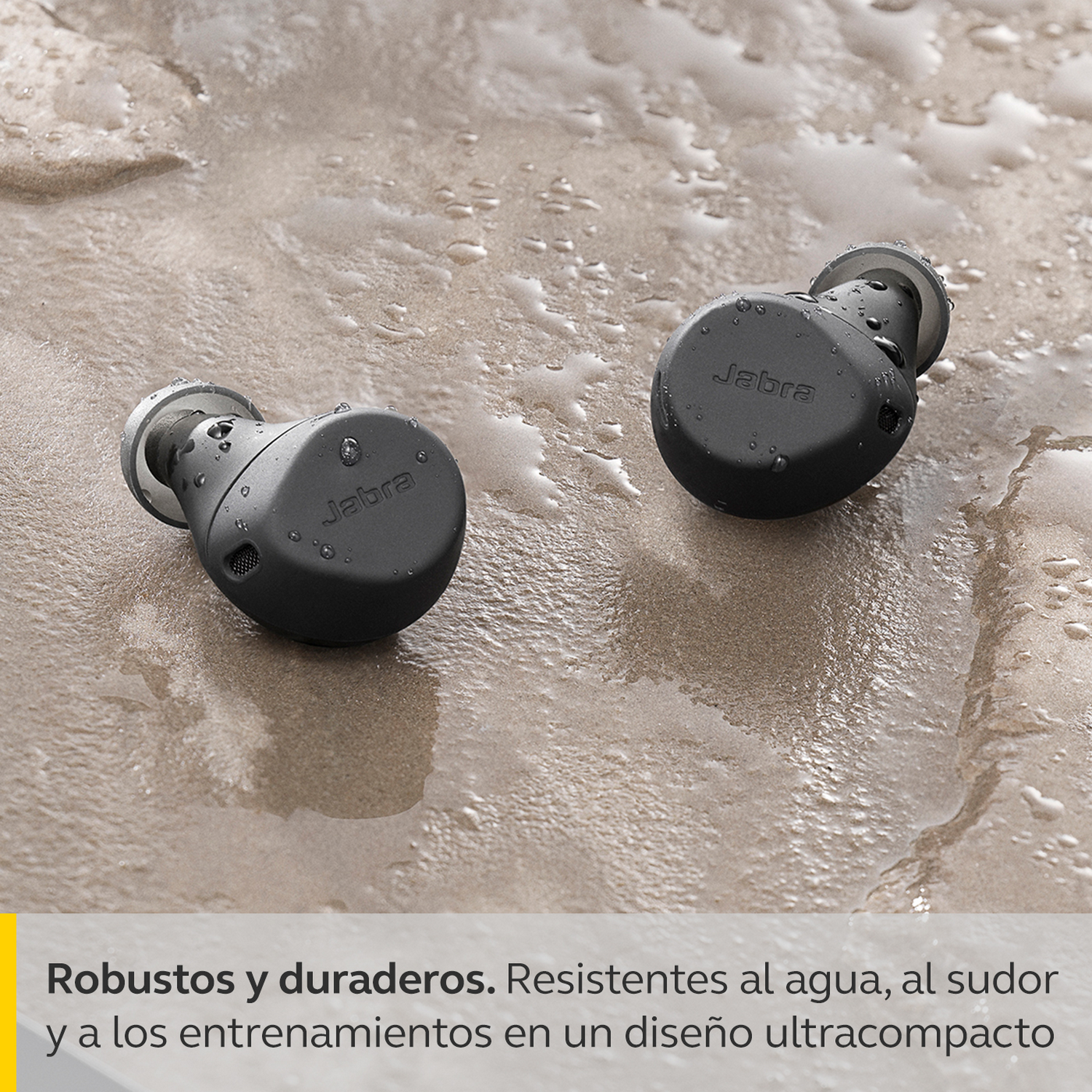 Auriculares inalámbricos negros en un estuche de carga, sobre una superficie arenosa y húmeda con texto debajo.