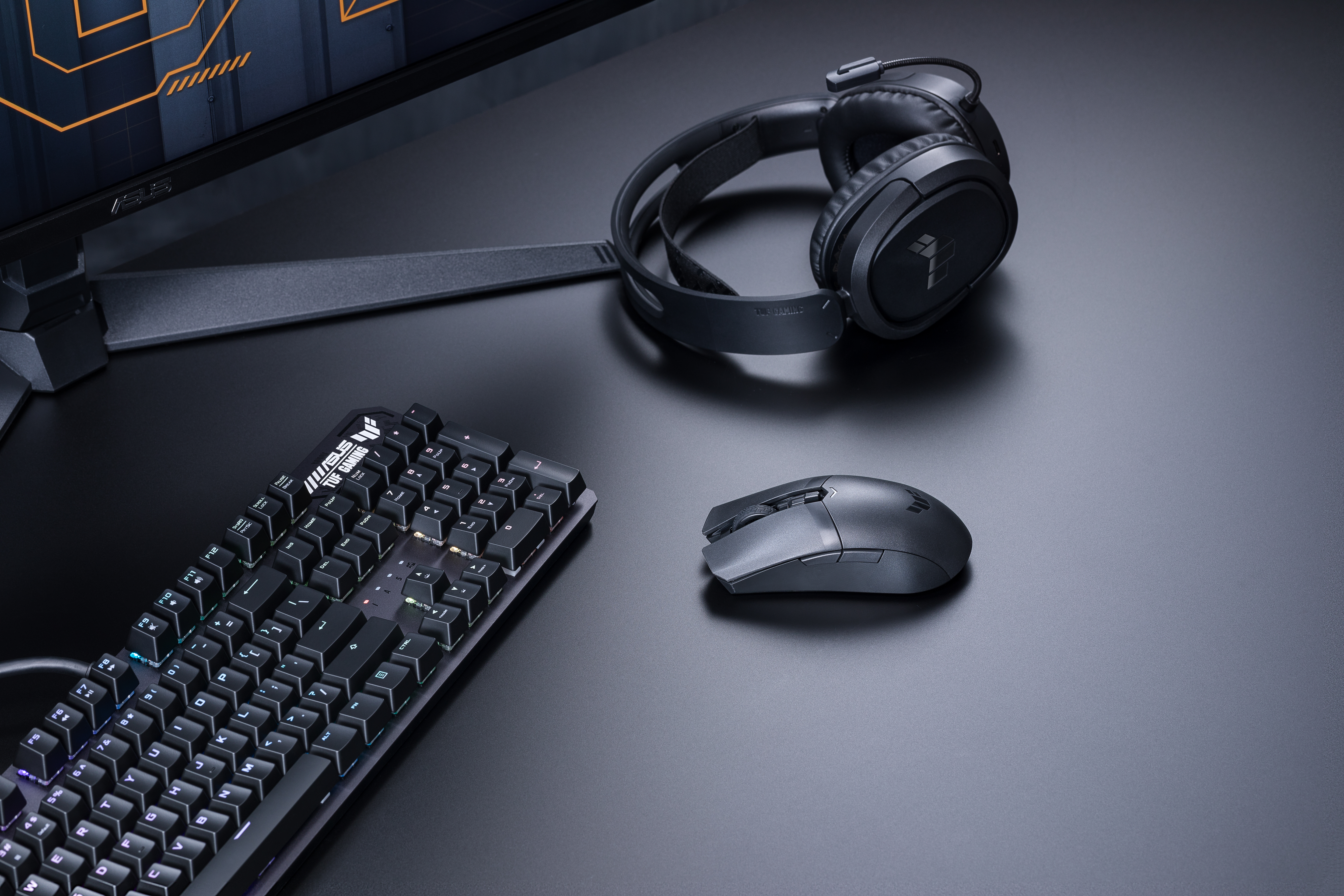 Schwarze Gaming-Tastatur, Maus und Kopfhörer auf schwarzem Schreibtisch.