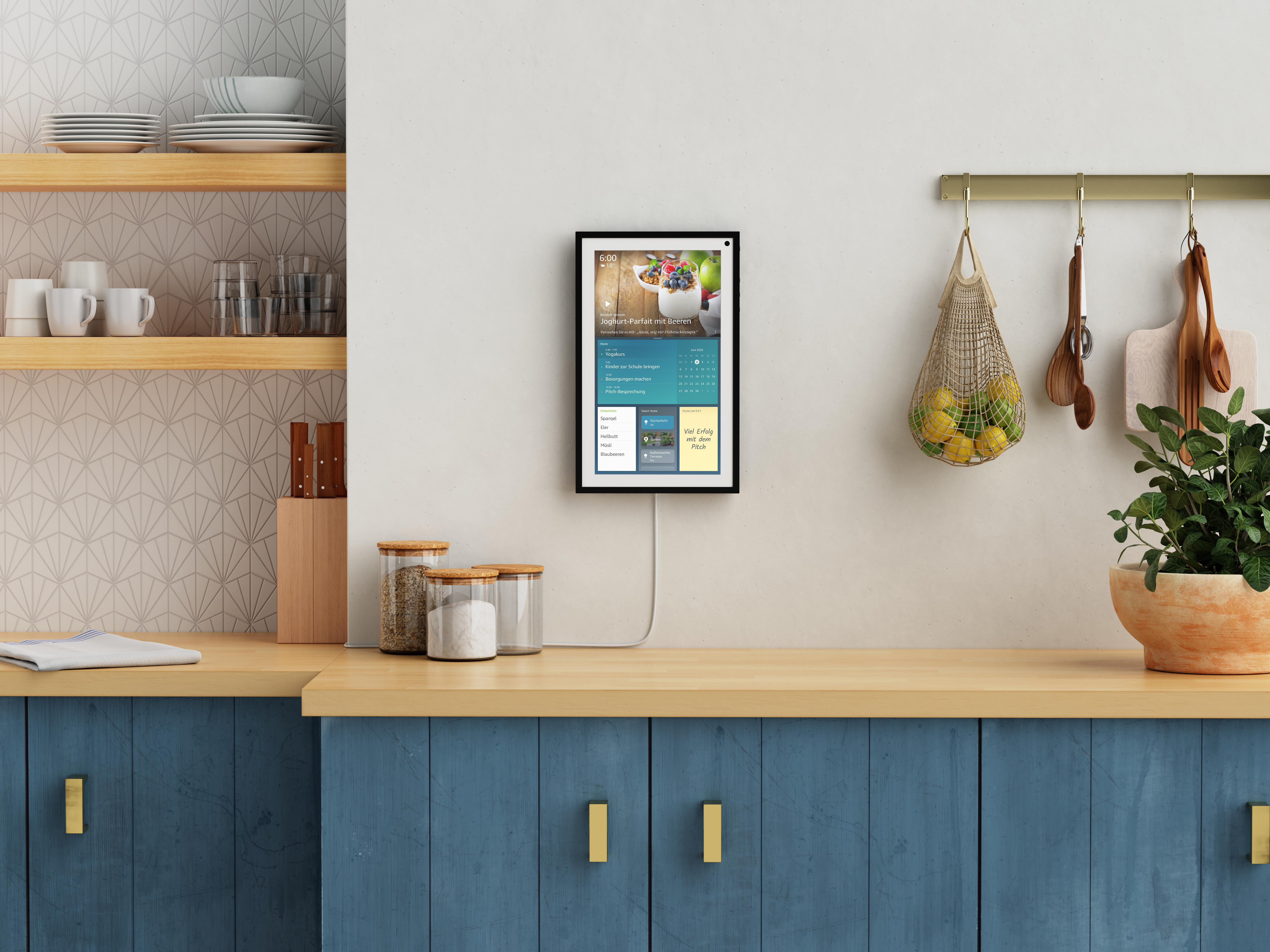 Küchenszene mit Smart Display. Holztresen, blaue Schränke und Utensilien.
