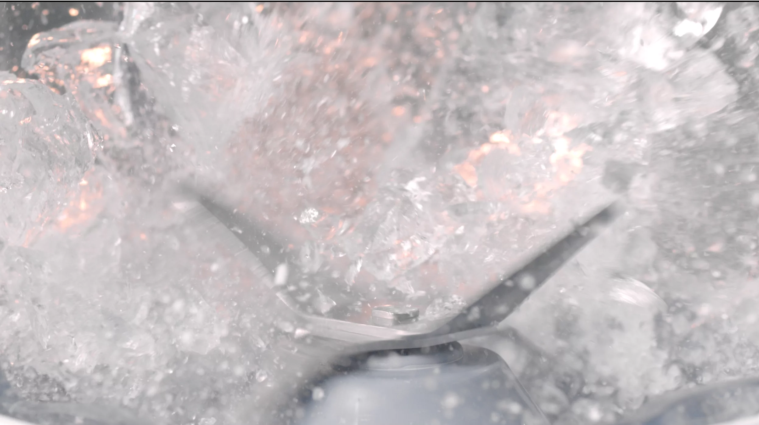 Gros plan d'un mixeur avec de la glace et de l'eau, créant un mélange glacé tourbillonnant.