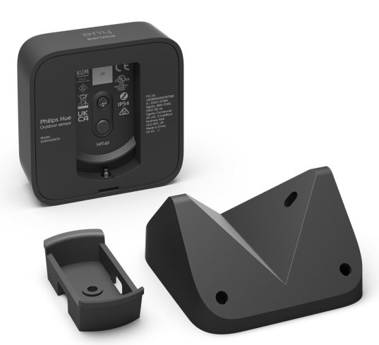 Un capteur extérieur Philips Hue noir avec un support de montage et un support séparé. L'arrière du capteur est visible.