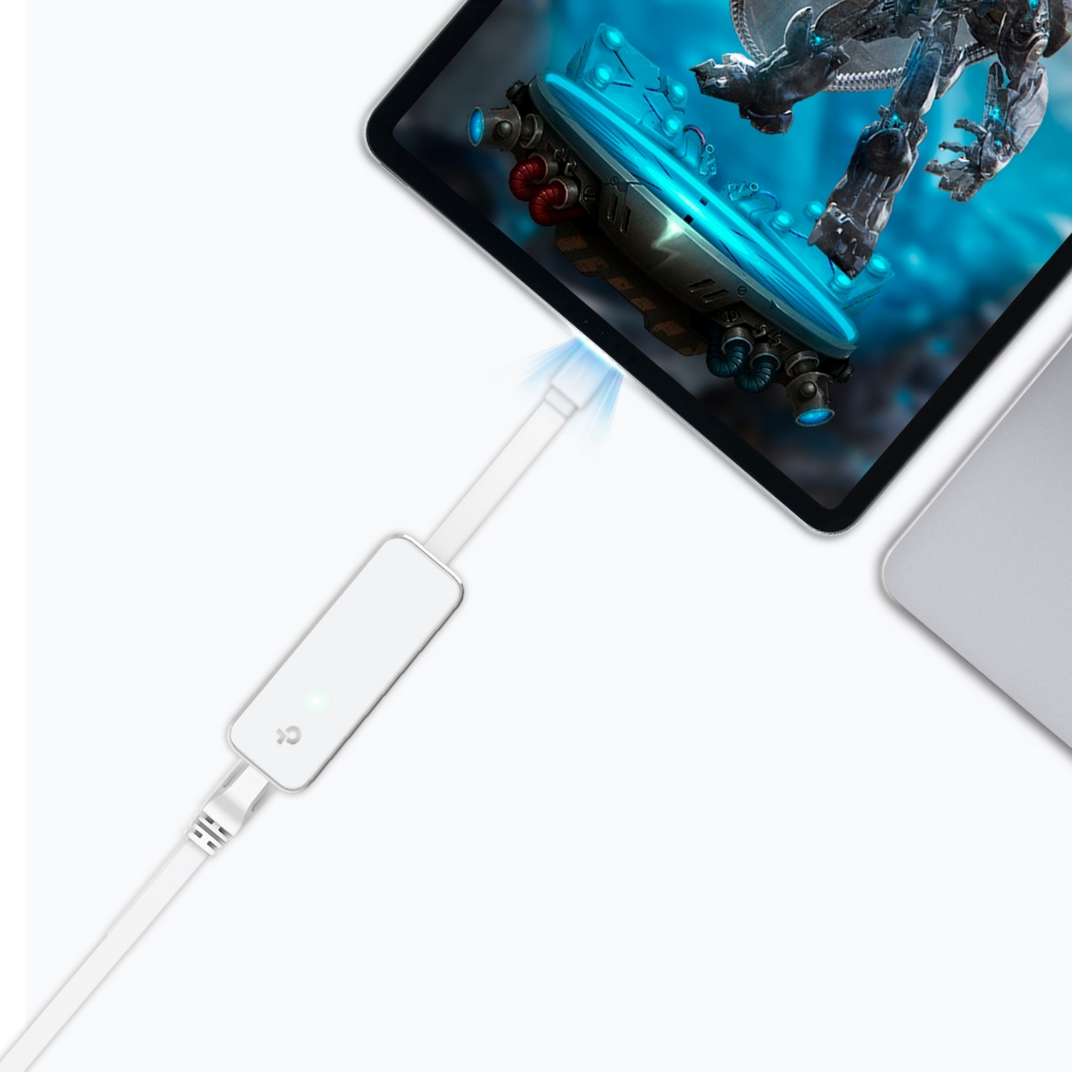 Un adaptador blanco con un cable blanco está conectado a una tableta y un portátil. La tableta muestra un juego.