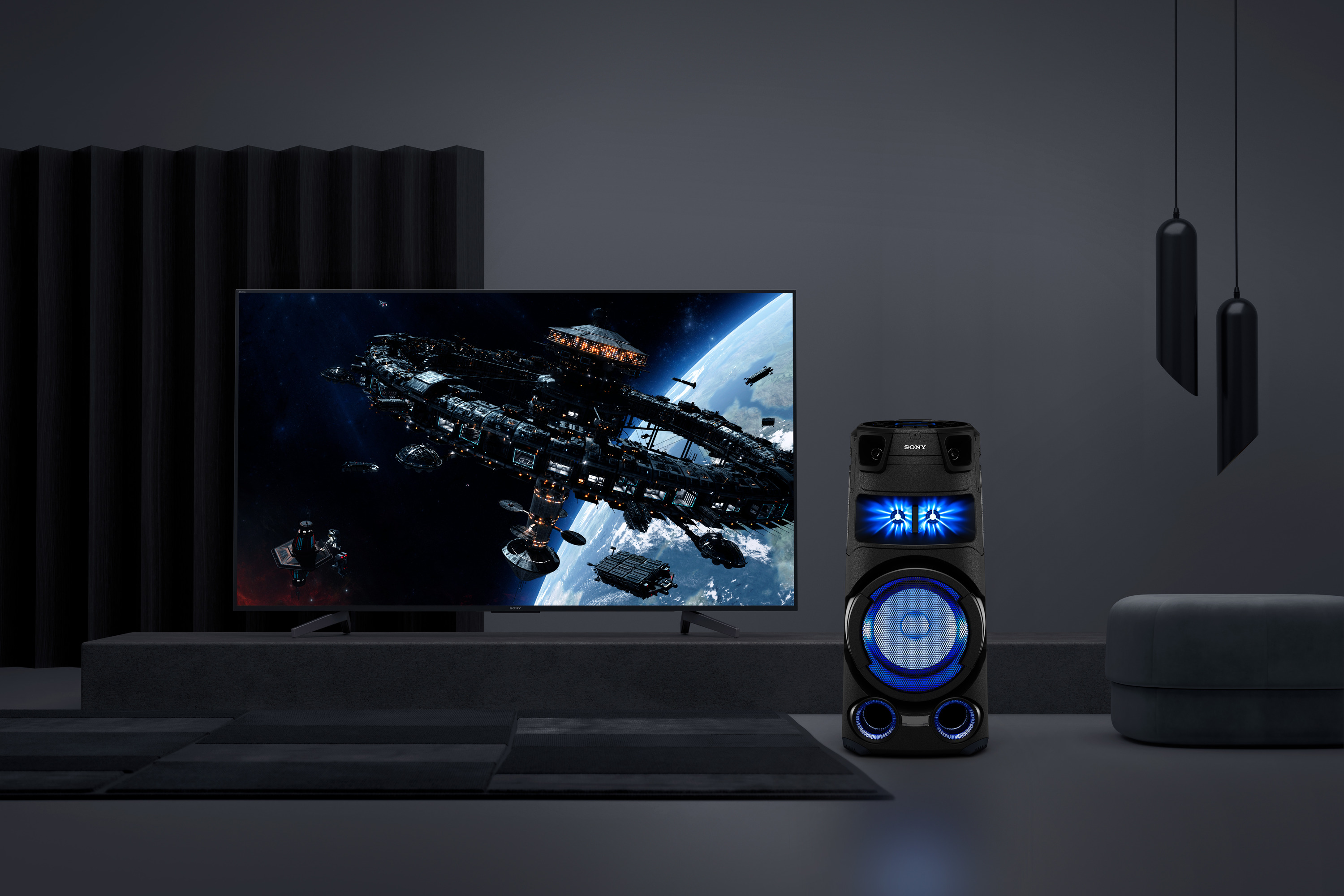 Habitación oscura con TV mostrando nave espacial, altavoz y taburete.