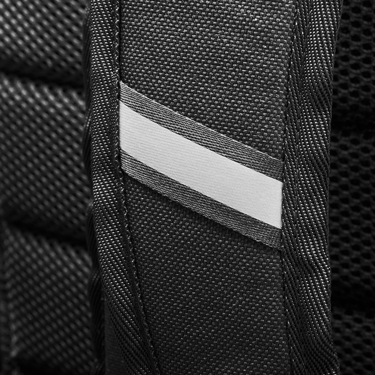 Primo piano di un cinturino nero per zaino con una striscia bianca riflettente.