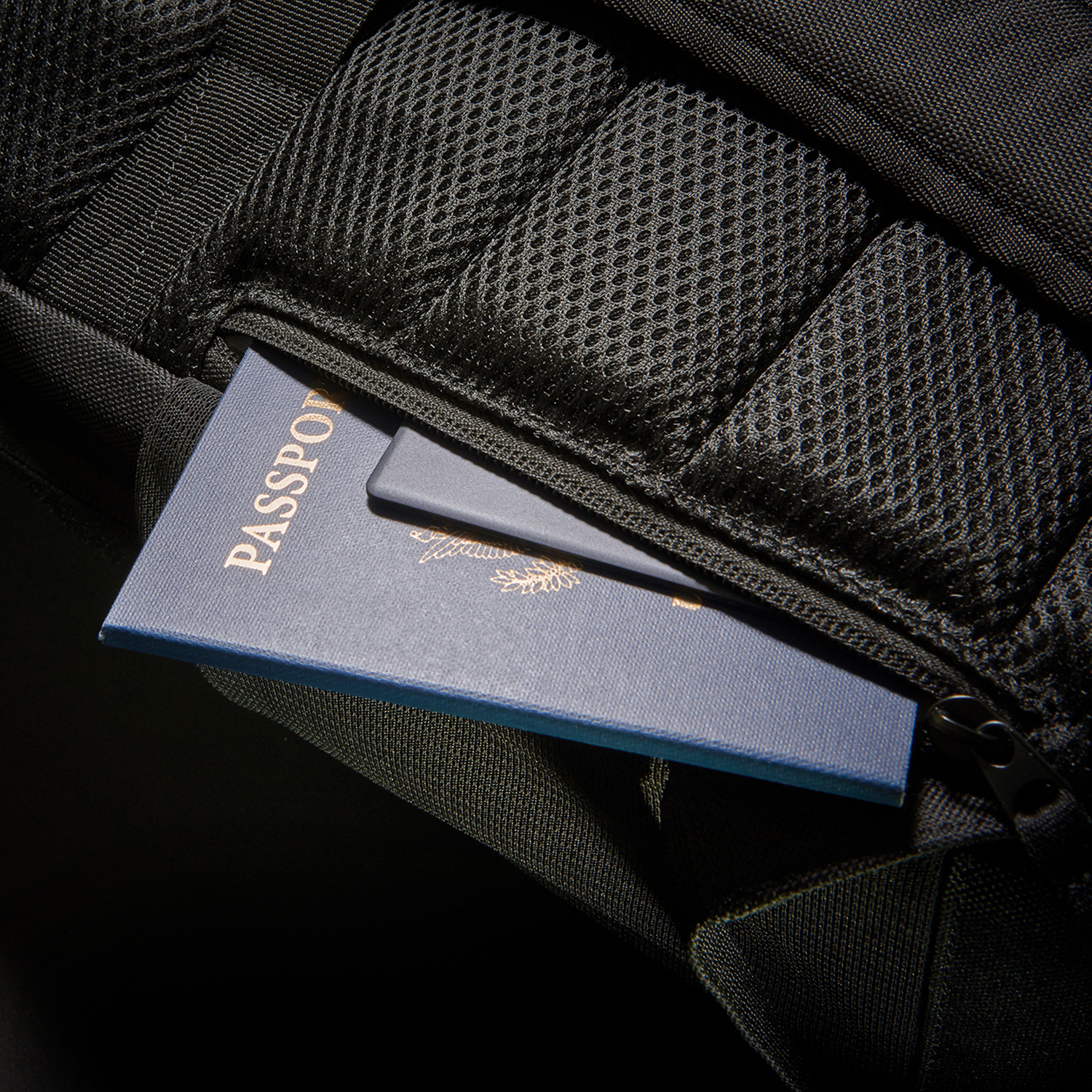 Uno zaino nero con un passaporto blu visibile nella tasca interna.