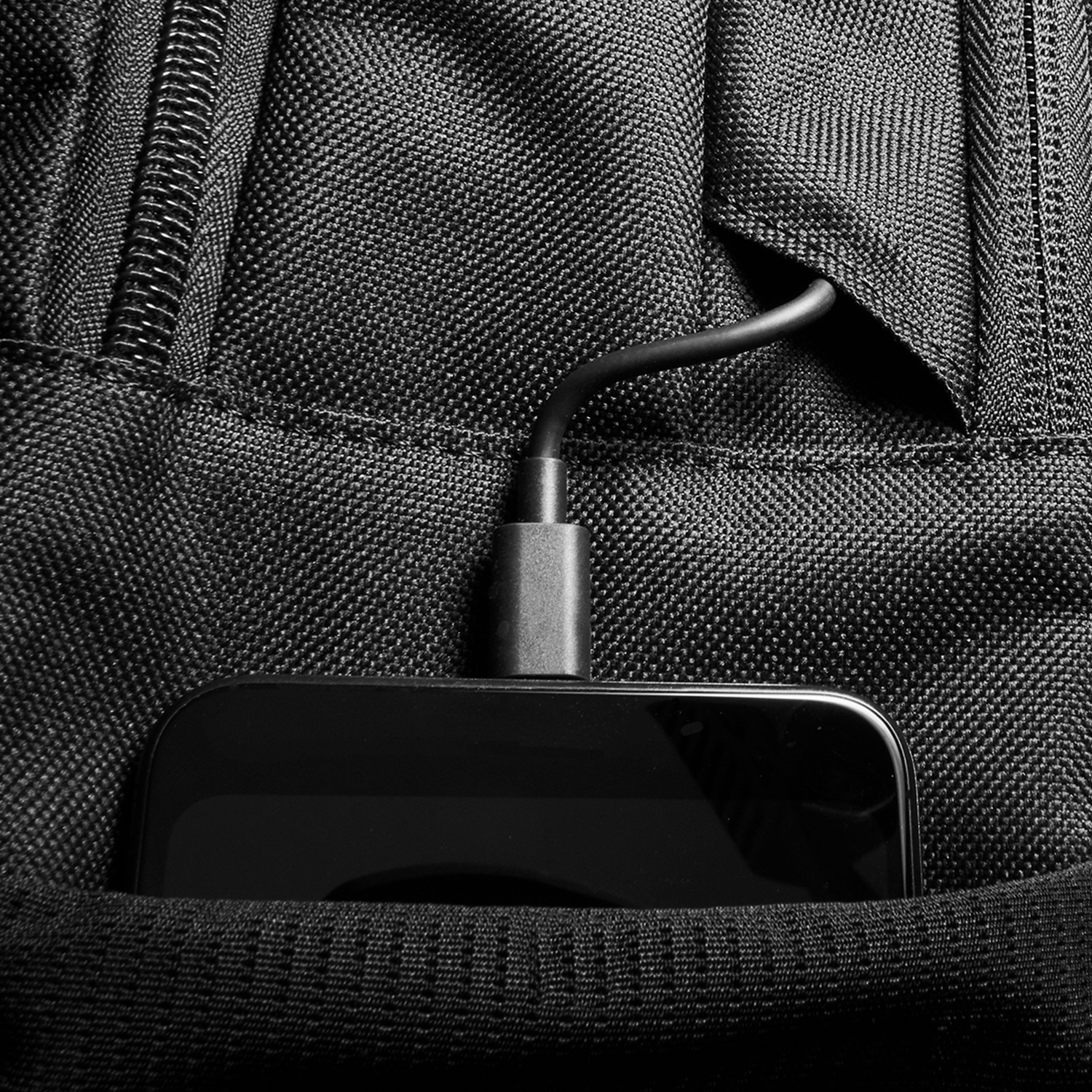 Tasca di zaino nero con cavo USB-C nero collegato a dispositivo nero.