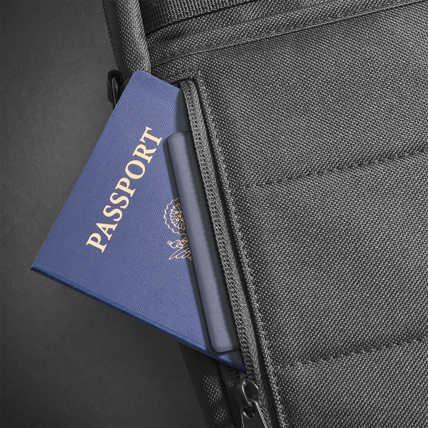 Passaporto parzialmente all'interno di una tasca di una borsa nera. La parola 'PASSPORT' è visibile sulla copertina blu.