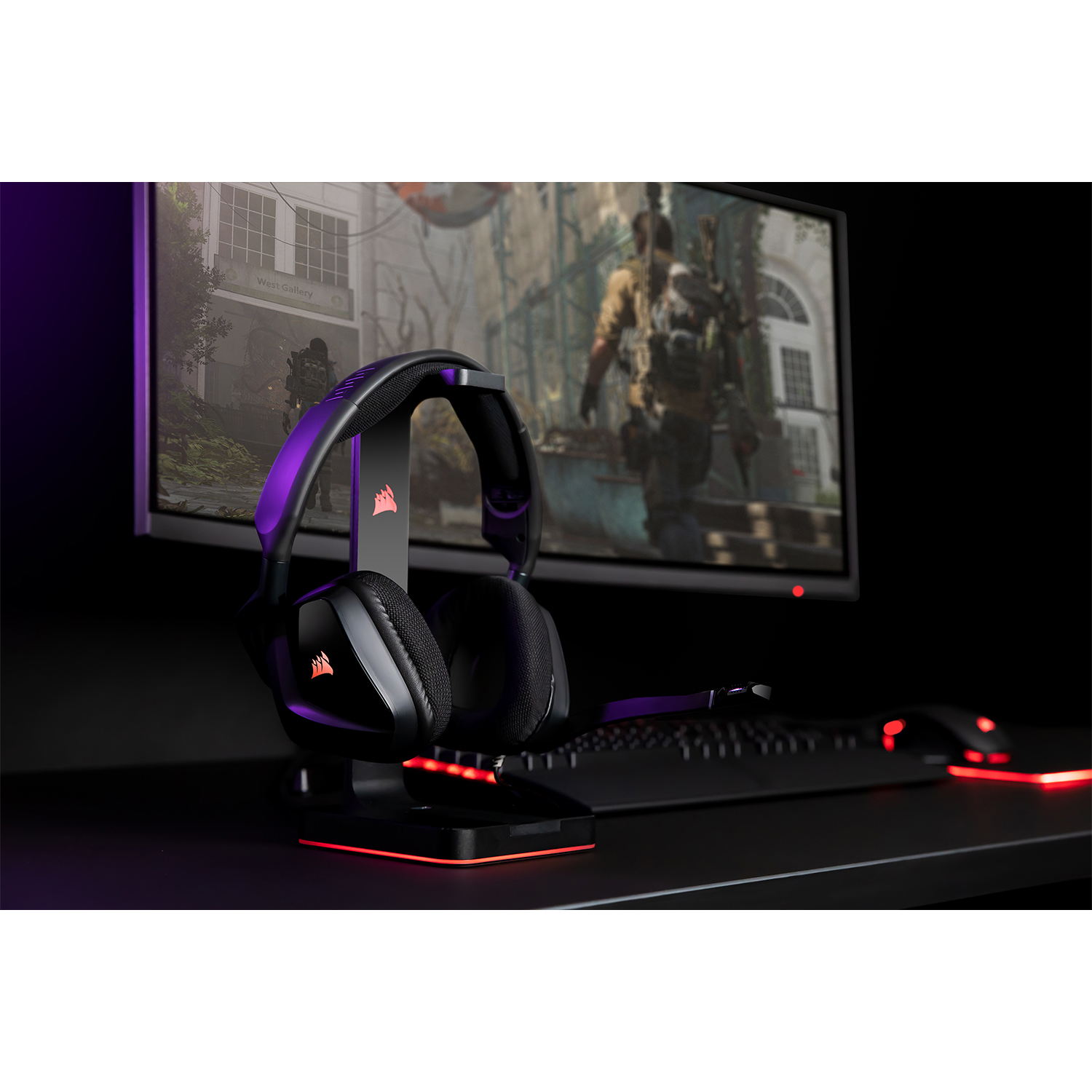 Un headset da gioco su un supporto accanto a un monitor che mostra una scena di videogioco.
