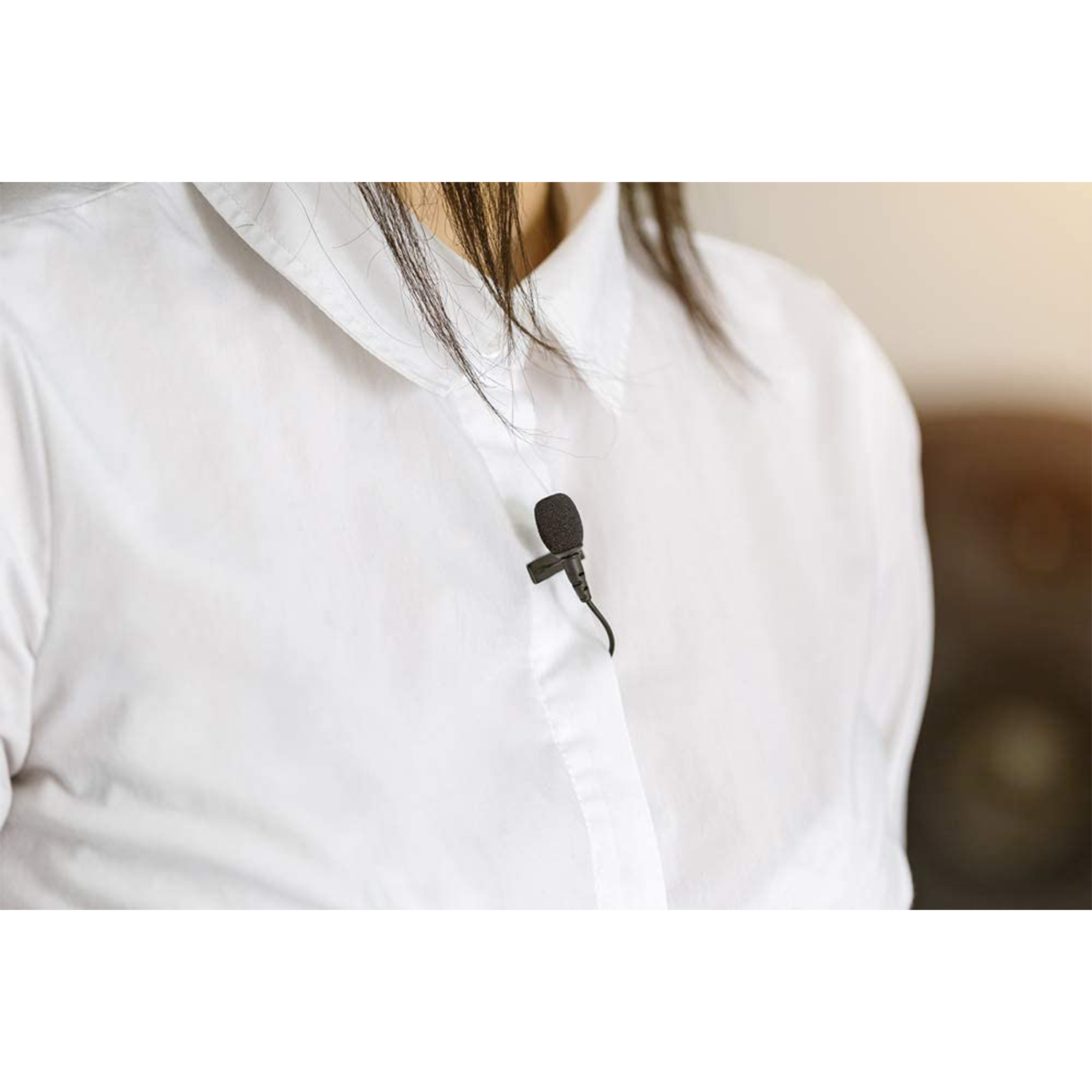 Una persona con una camicia bianca ha un microfono a bavero nero attaccato al colletto.