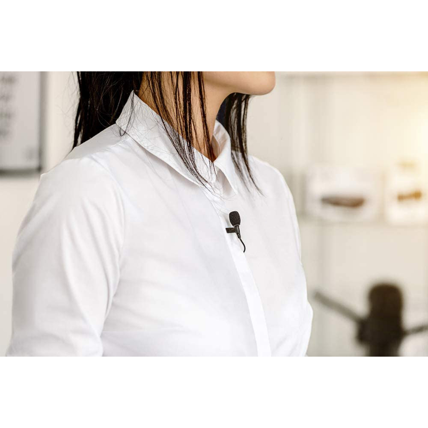 Una donna con una camicia bianca con un piccolo microfono nero attaccato al colletto.