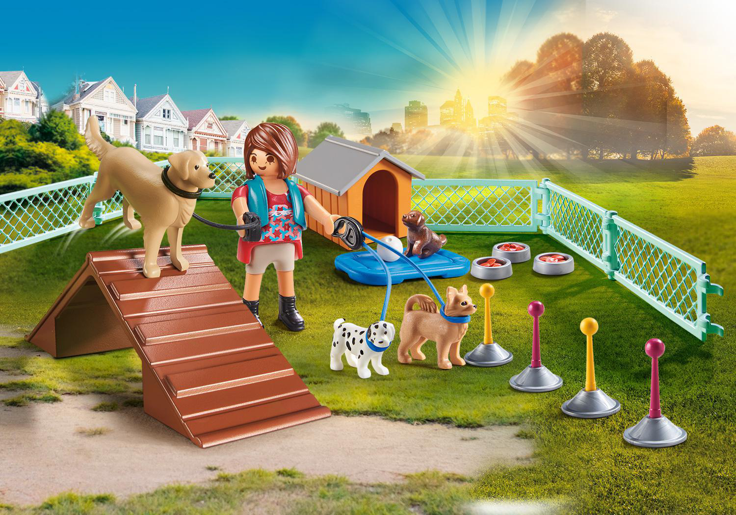 Eine Spielzeug-Hundeparkszene. Eine Frau mit Hunden, Hindernissen, Hundehütten und Futternäpfen. Häuser und eine Stadtlandschaft im Hintergrund.