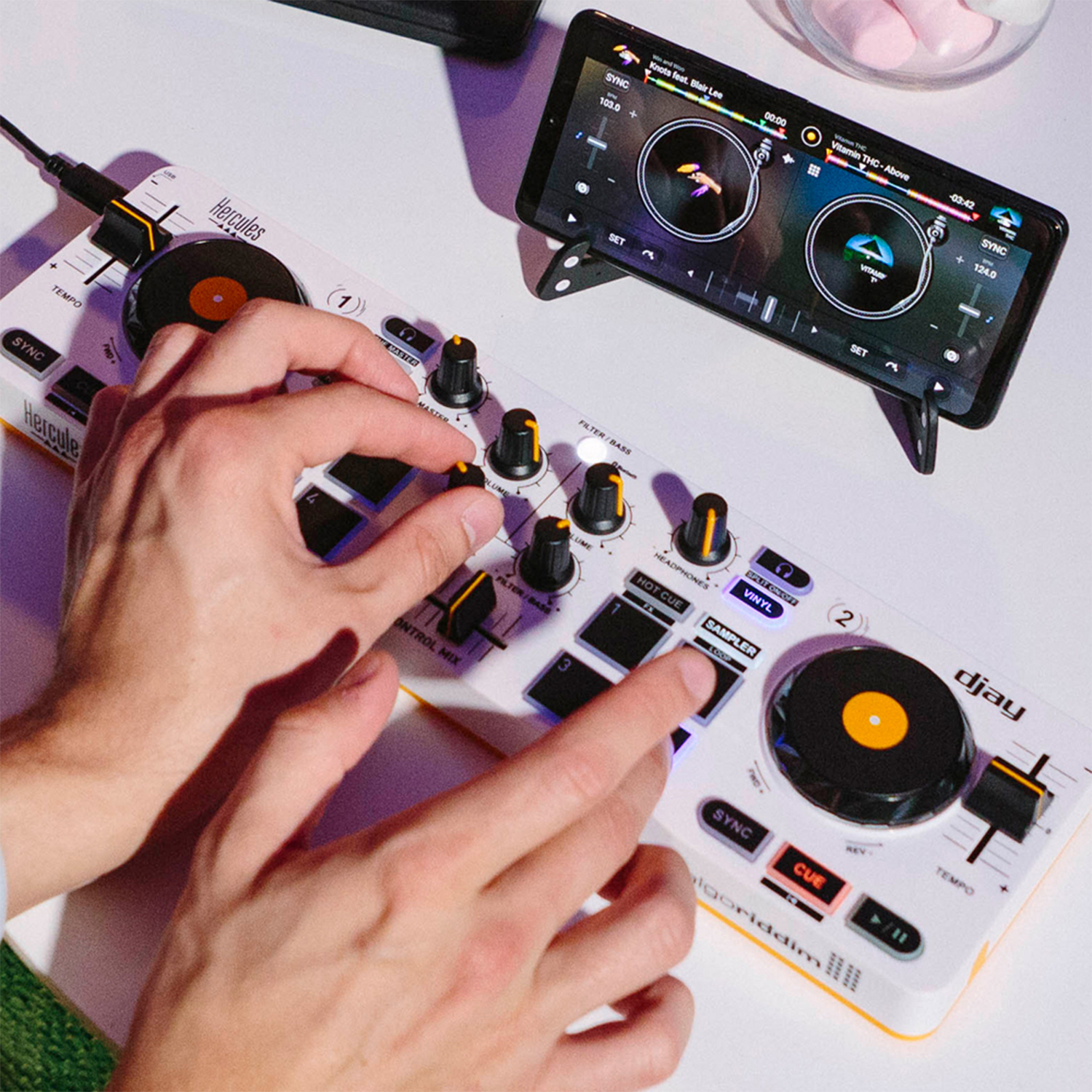 Controller DJ con comandi manuali e smartphone che mostra l'interfaccia musicale.