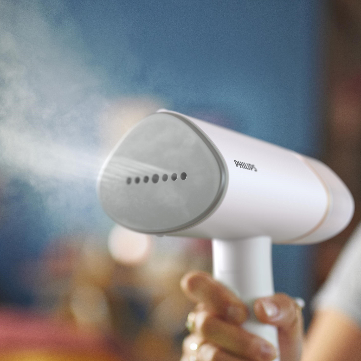 Un vaporizzatore portatile Philips bianco e grigio con vapore. Tenuto da una mano.