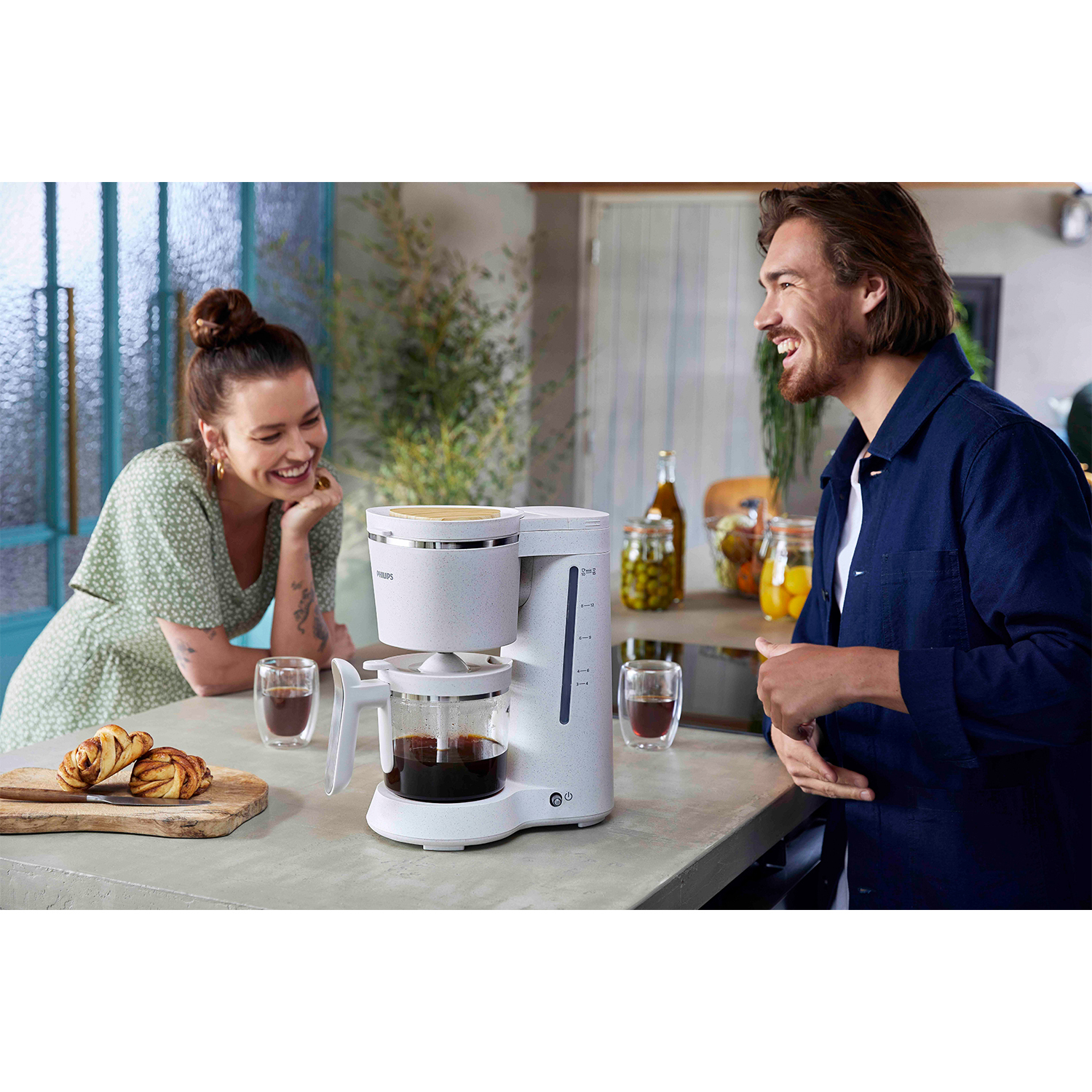 Coppia che si sorride a vicenda mentre prepara il caffè con una caffettiera bianca.
