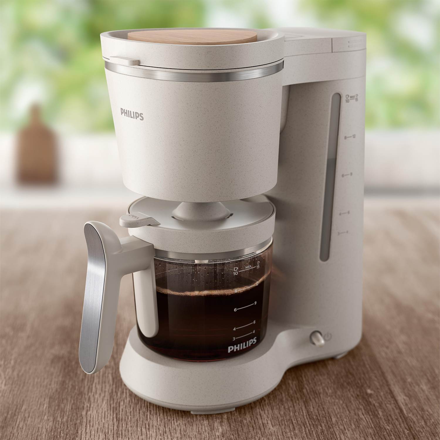 Una caffettiera beige con una caraffa di vetro e un coperchio di legno.