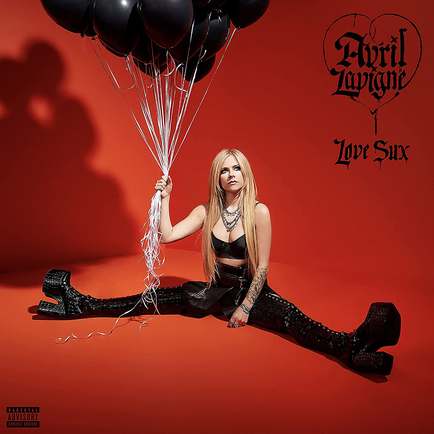 Avril Lavigne piros háttéren fekete lufikat tart. Album borító, 'Love Sux' felirat.