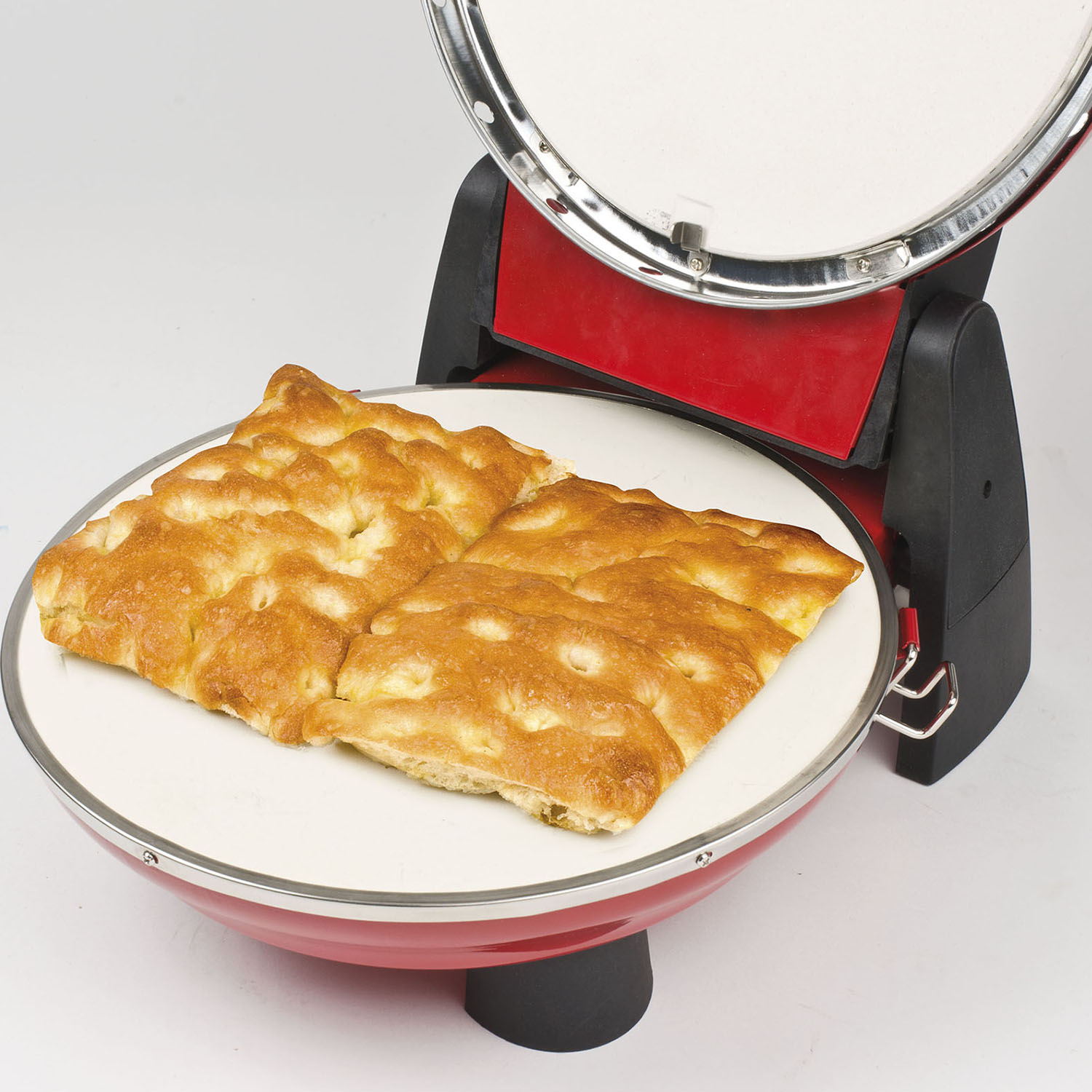 Un forno per pizza rosso con pane focaccia su una pietra di ceramica bianca. Il forno è aperto.