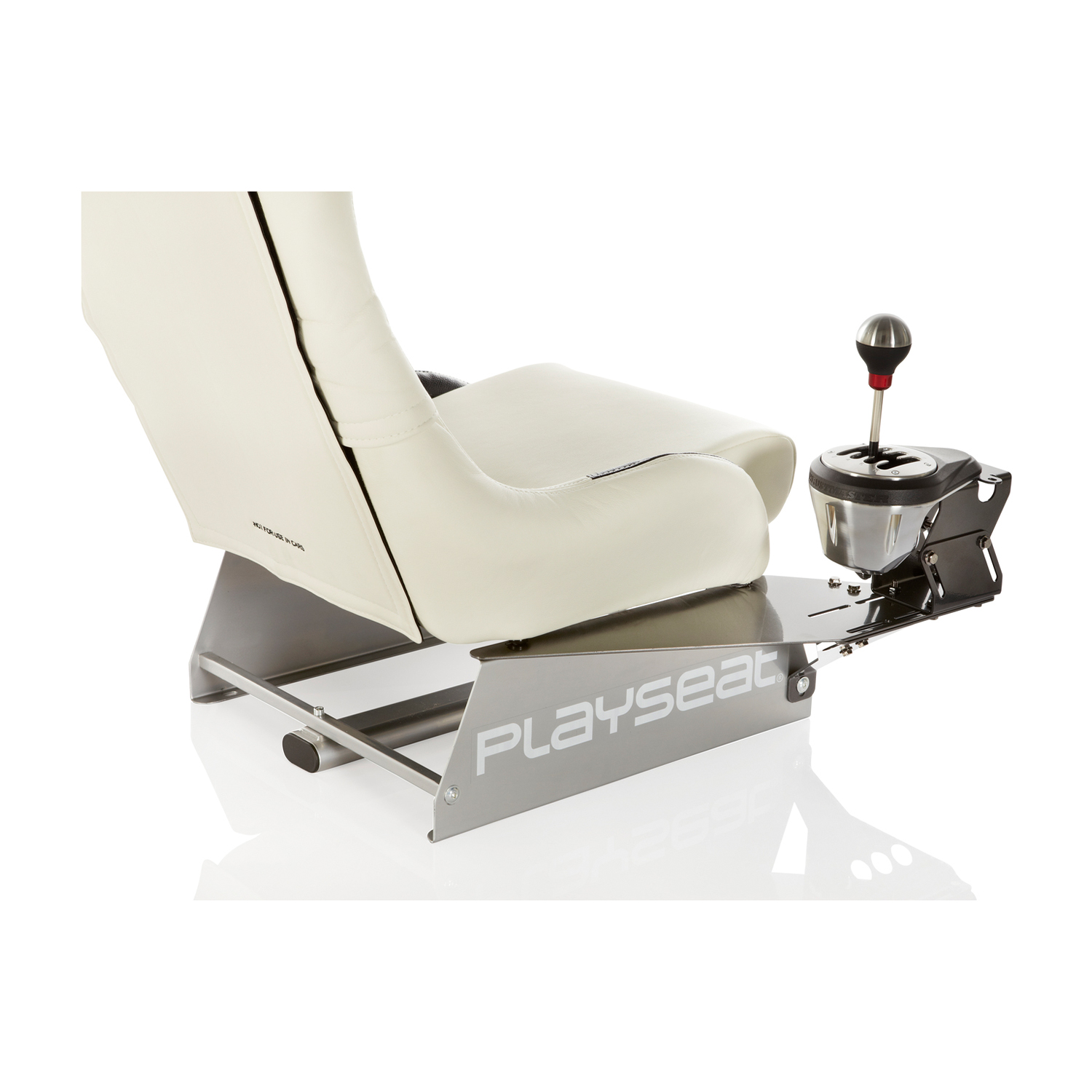Sedia da corsa bianca con cambio montato. 'PLAYSEAT' stampato sulla base. Sfondo bianco.