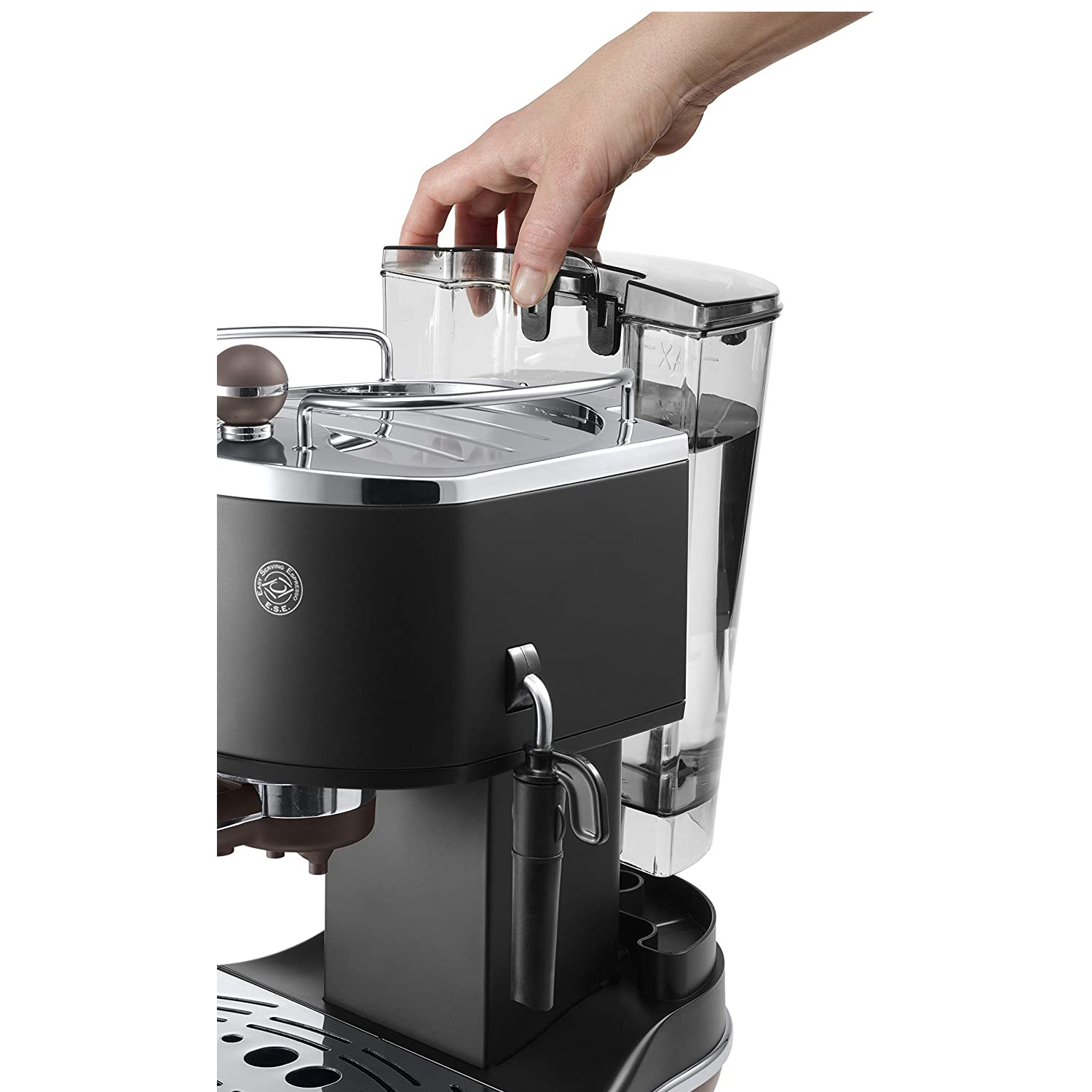 Una mano aggiunge acqua a una macchina da caffè espresso nera e argento, primo piano.