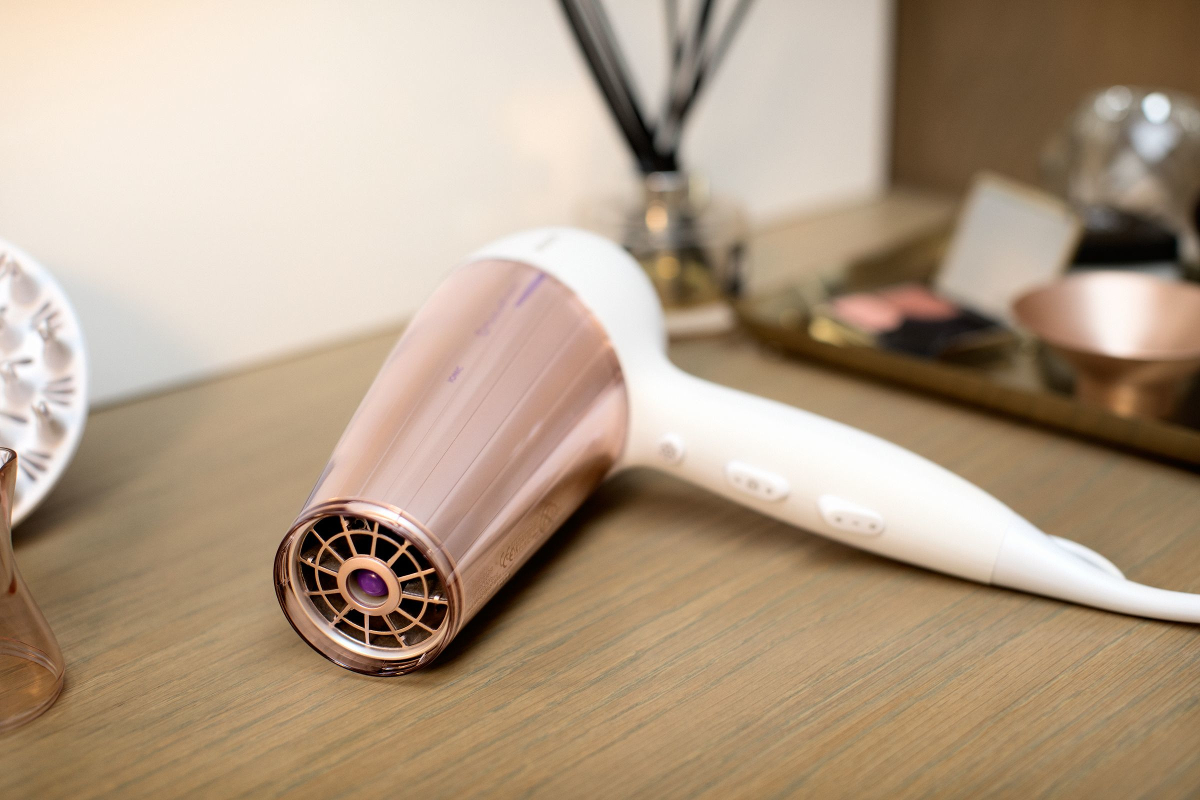 Haardroger op een houten oppervlak. Roze goud en wit kleurenschema.