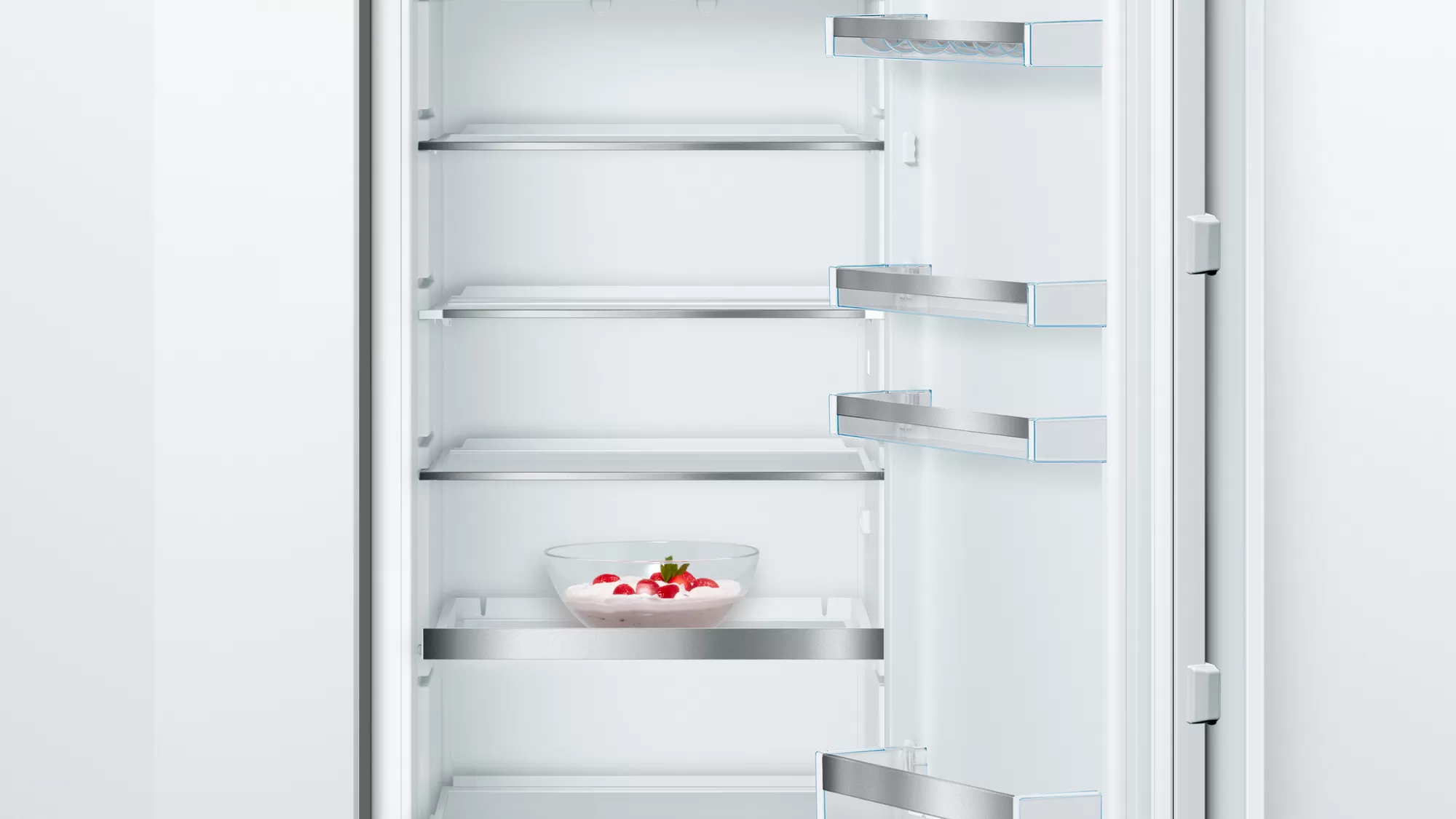 Innenraum eines weißen Kühlschranks mit Regalen und einer Schüssel Erdbeeren.