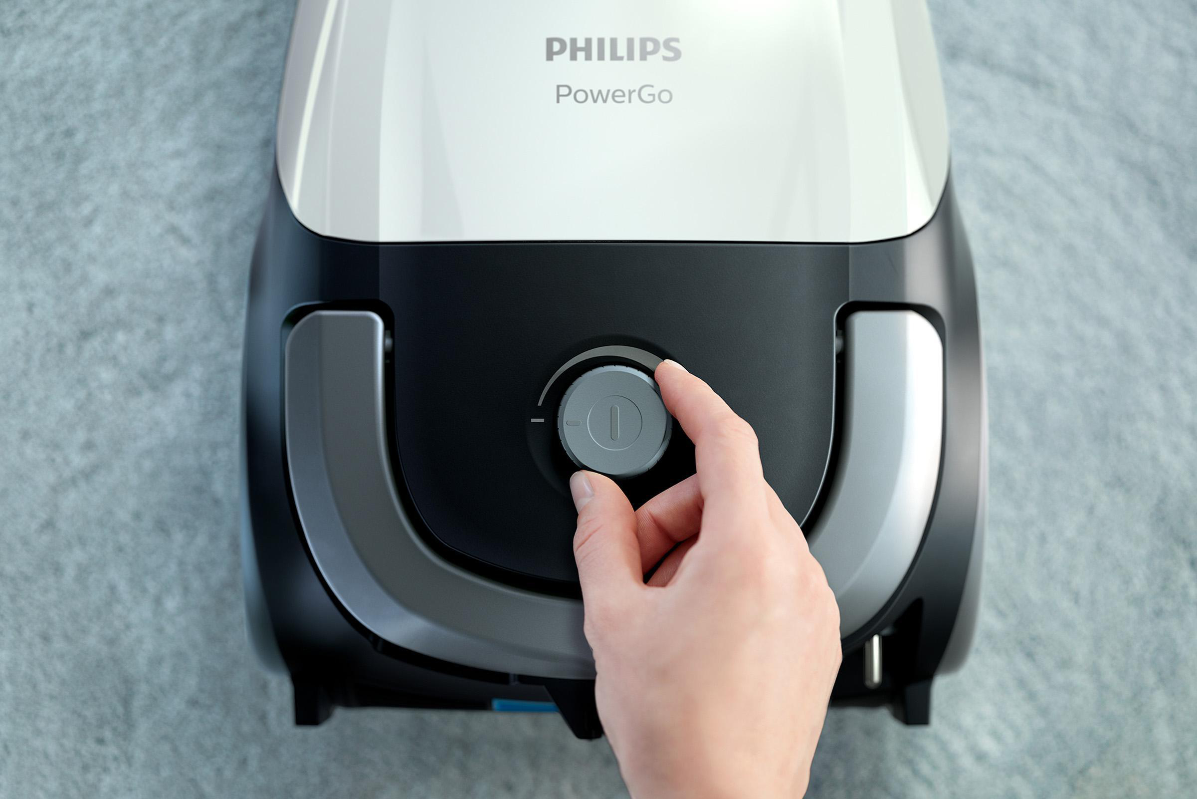 Die Hand einer Person, die einen Drehregler an einem weiß-schwarzen Philips PowerGo Staubsauger einstellt.