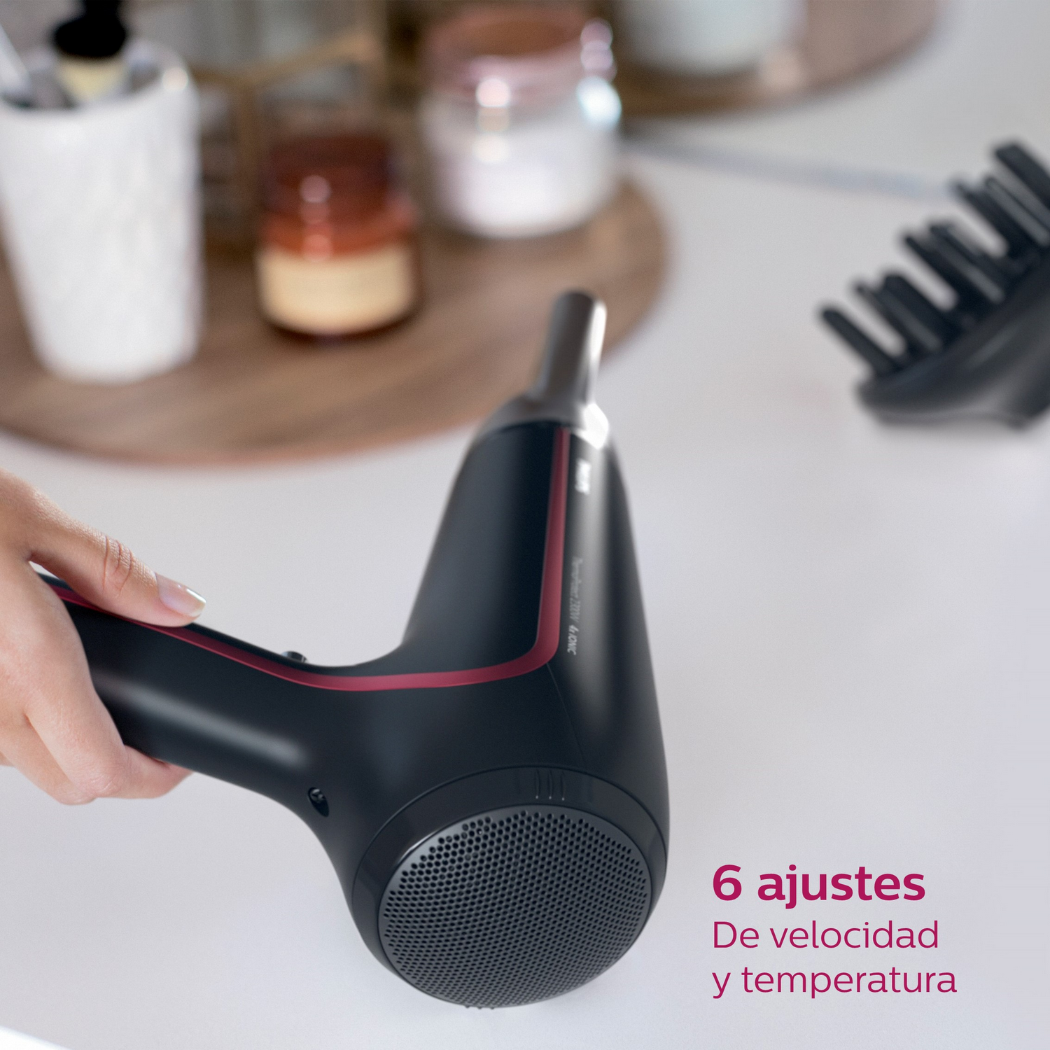 Secador de pelo negro y rojo en superficie blanca, con texto de ajustes.