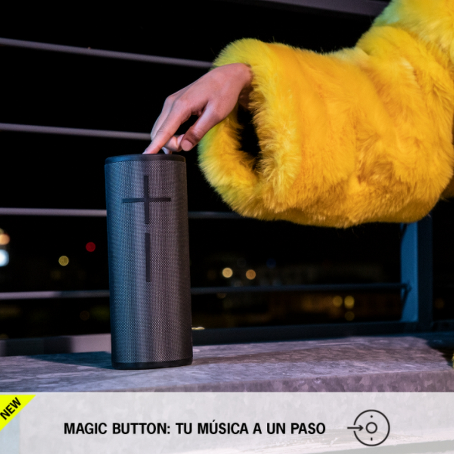 Una mano sobre un altavoz negro con un abrigo de piel amarillo.