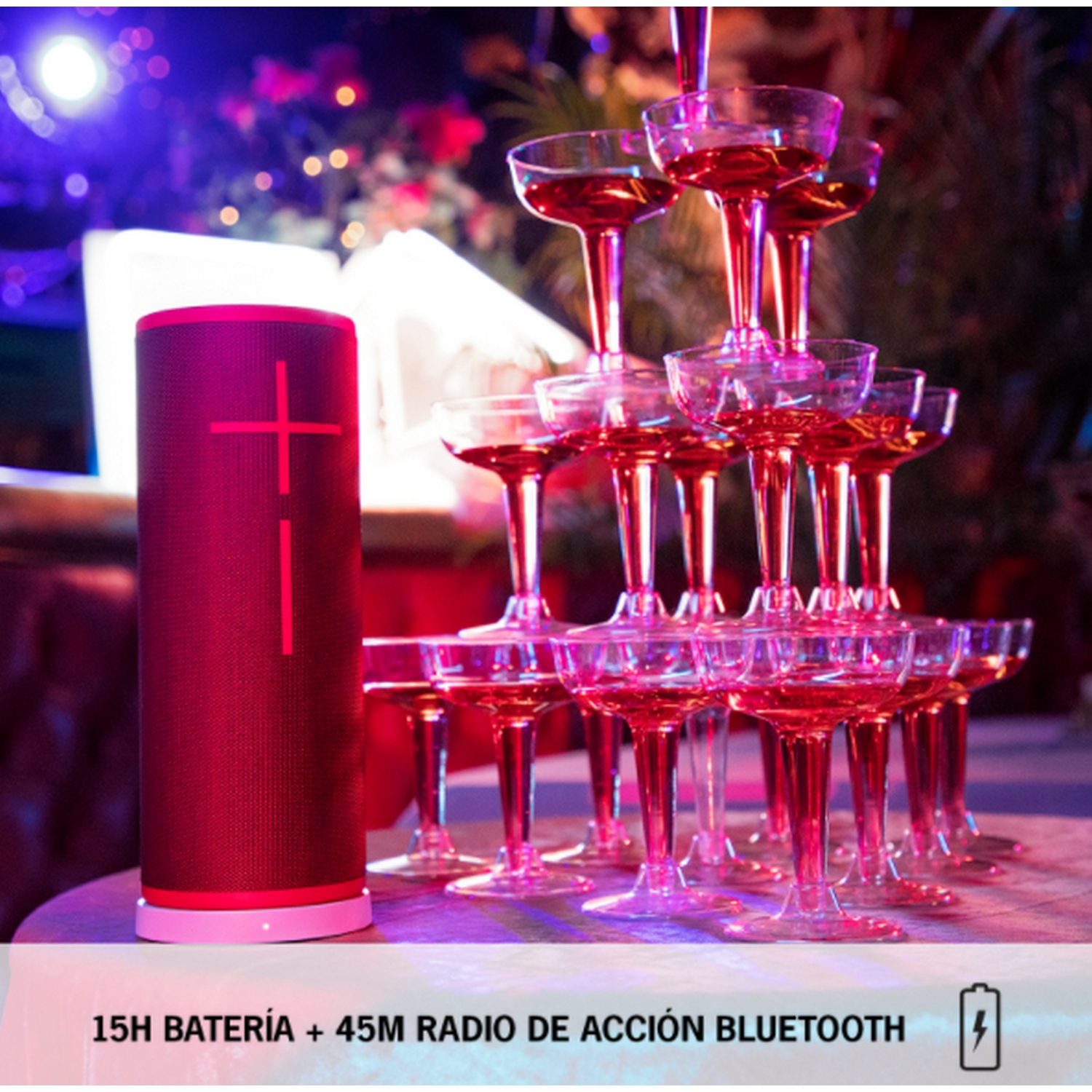 Altavoz cilíndrico rosa junto a una pirámide de copas de champán con líquido rojo.