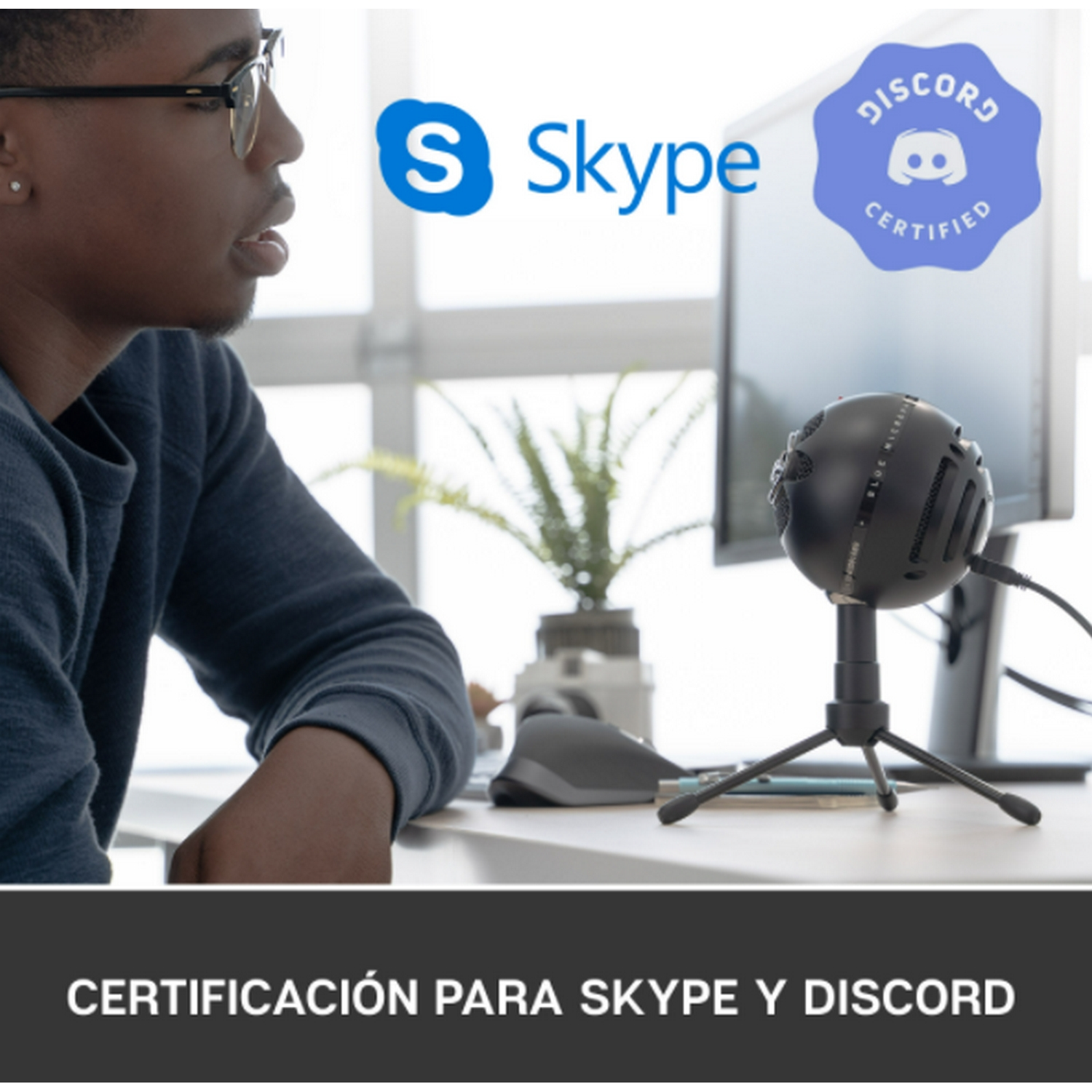 Hombre con gafas frente a una computadora, micrófono y logos de Skype, Discord.