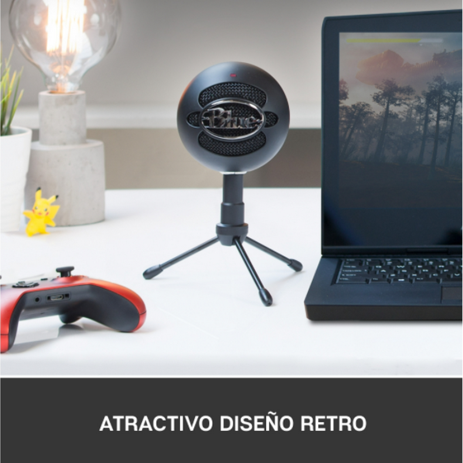 Un micrófono negro sobre un soporte, con un portátil y un mando de juegos en un escritorio blanco.