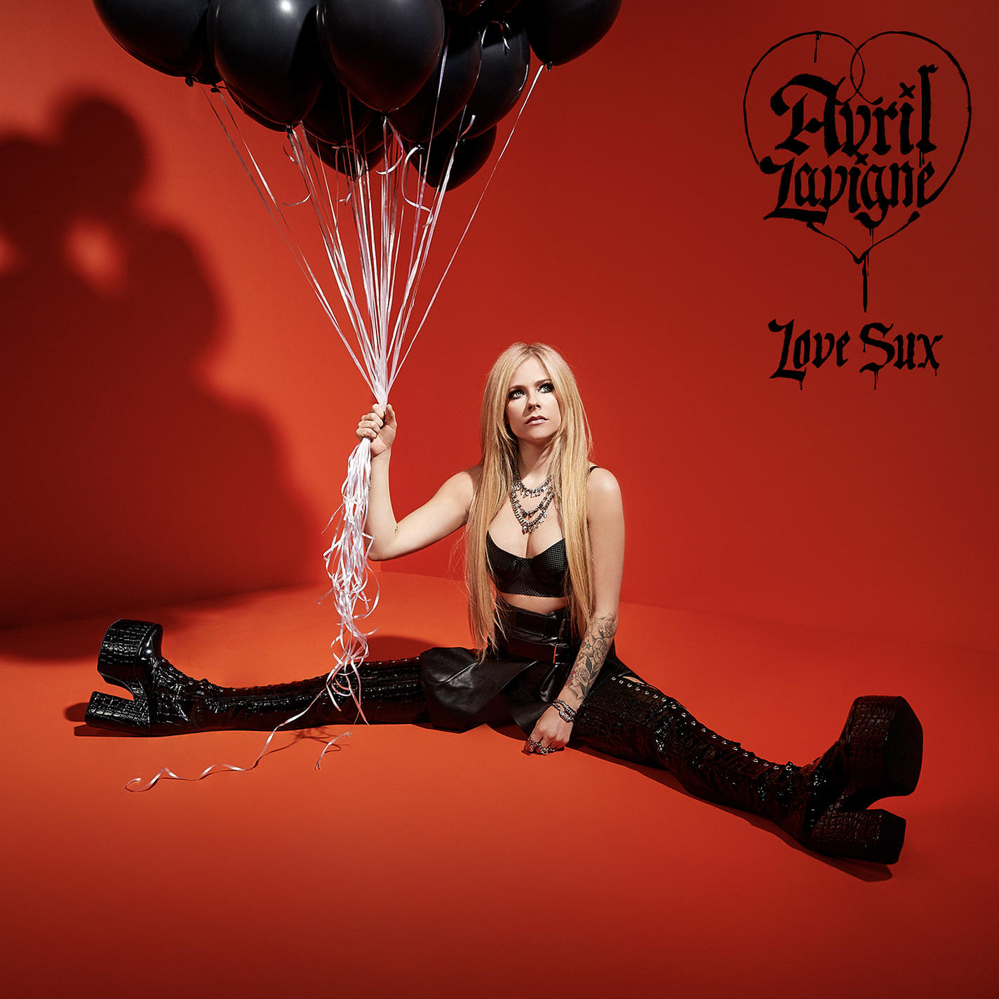 Avril Lavigne fekete ruhában, fekete lufikat tart. Piros háttér. Album borítója szöveggel.