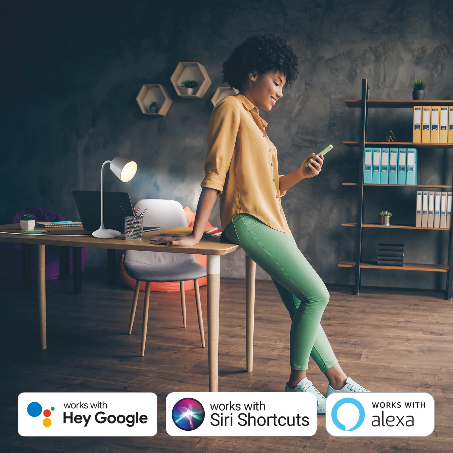 Una mujer apoyada en un escritorio, usando un teléfono. Los logotipos de casa inteligente están en la parte inferior.