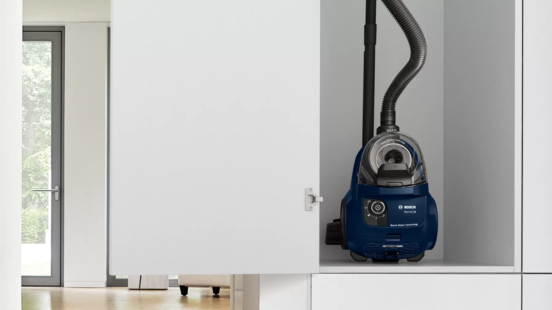 Vacuum cleaner in a white cabinet. The door is partially open, showing the appliance inside.