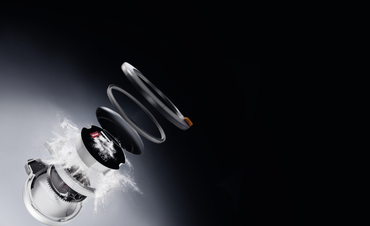 Exploded view van een stofzuiger die de componenten toont, onderdelen gescheiden en stof die vrijkomt.