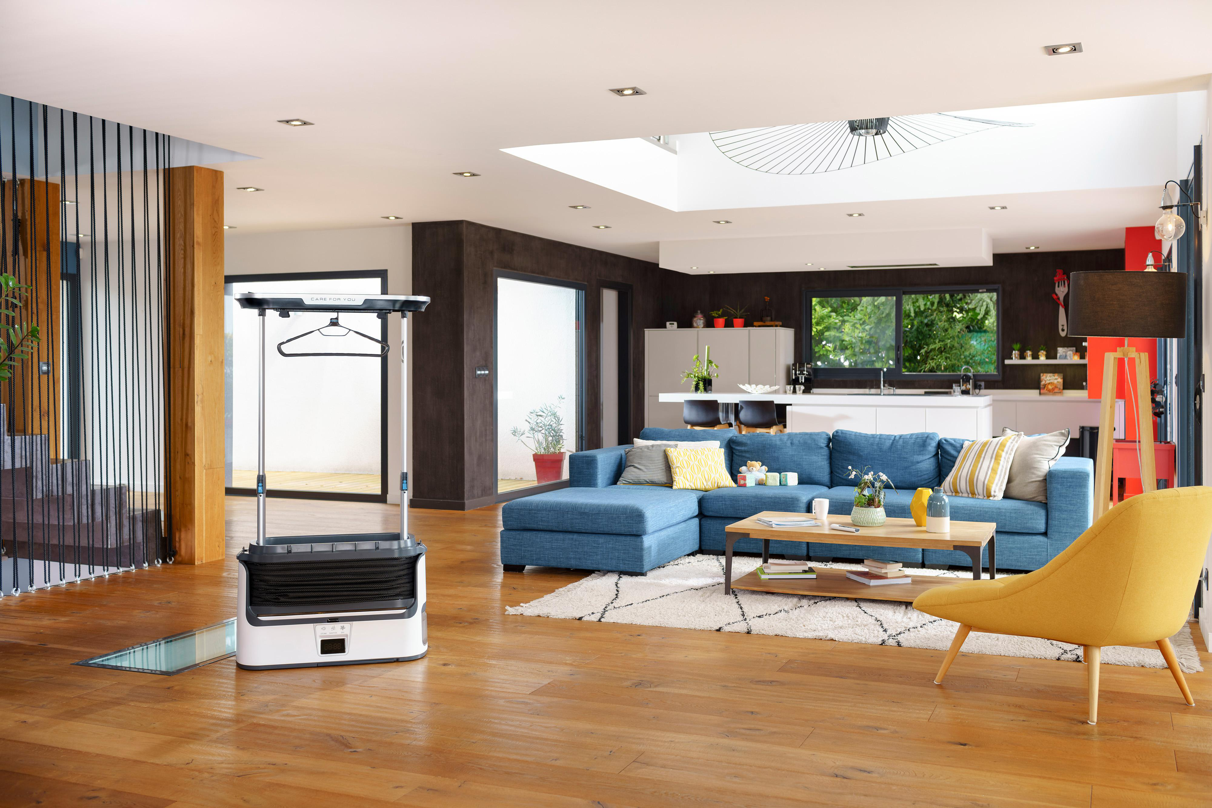Modernes Wohnzimmer mit blauem Ecksofa, Kleiderdampfer und Holzböden.
