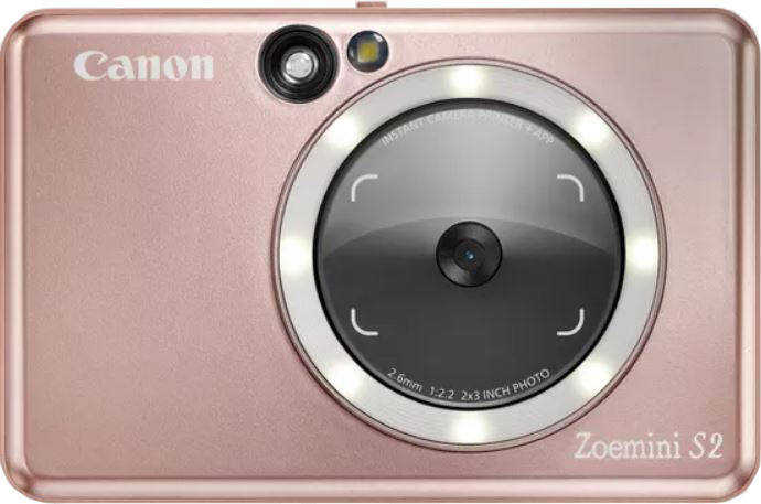 Rózsaszín arany Canon Zoemini S2 azonnali kamera, nagy objektívvel, fényekkel körülvéve.