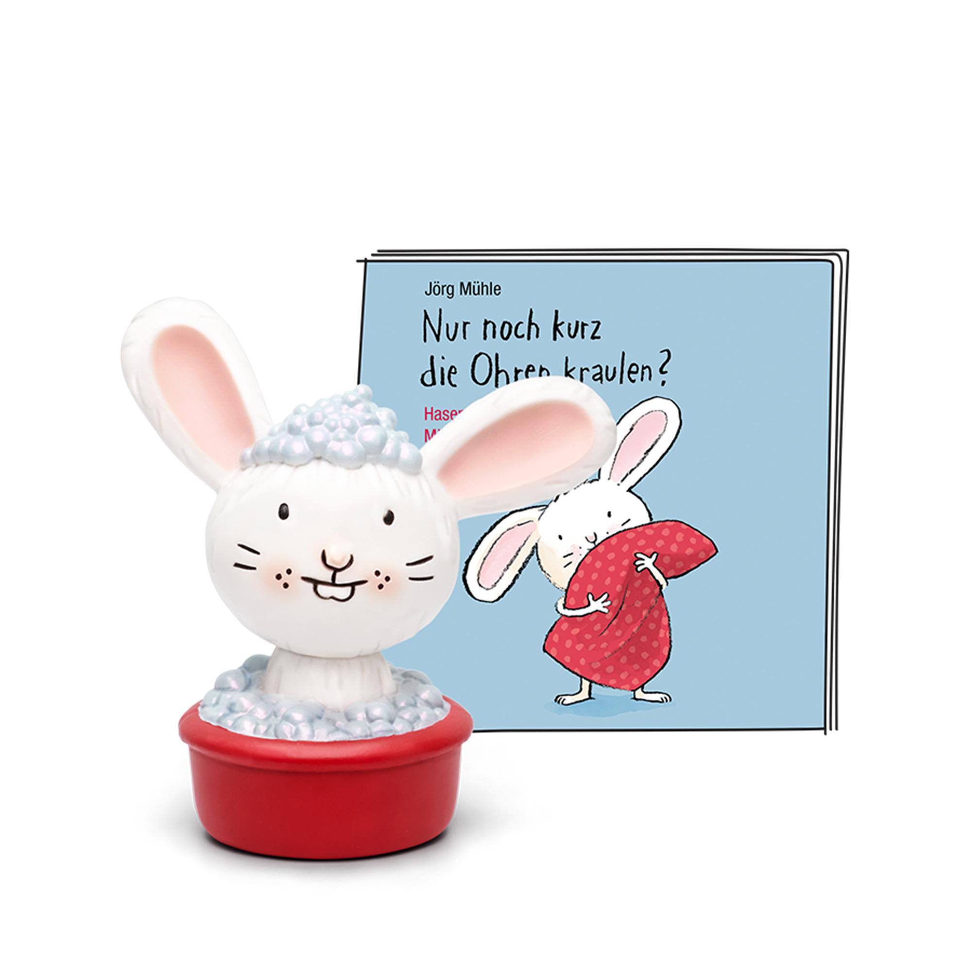 Eine weiße Hasenstatue in einer Wanne mit Blasen und ein Buch mit einer Hasenzeichnung.